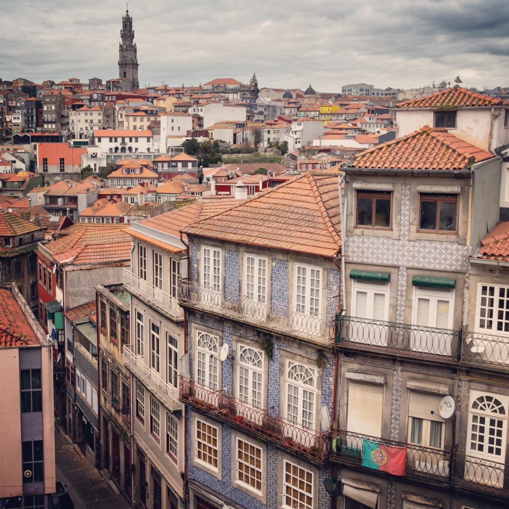 Panoramic view of Porto’s terracotta rooftops with the Clérigos Tower rising in the distance under a cloudy