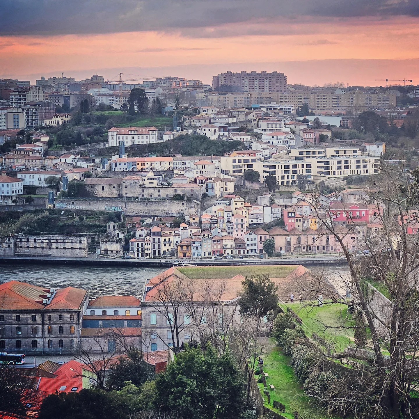 Layers of buildings with terracotta rooftops stretching toward the horizon, captured at sunset from Porto looking toward Vila Nova de Gaia.