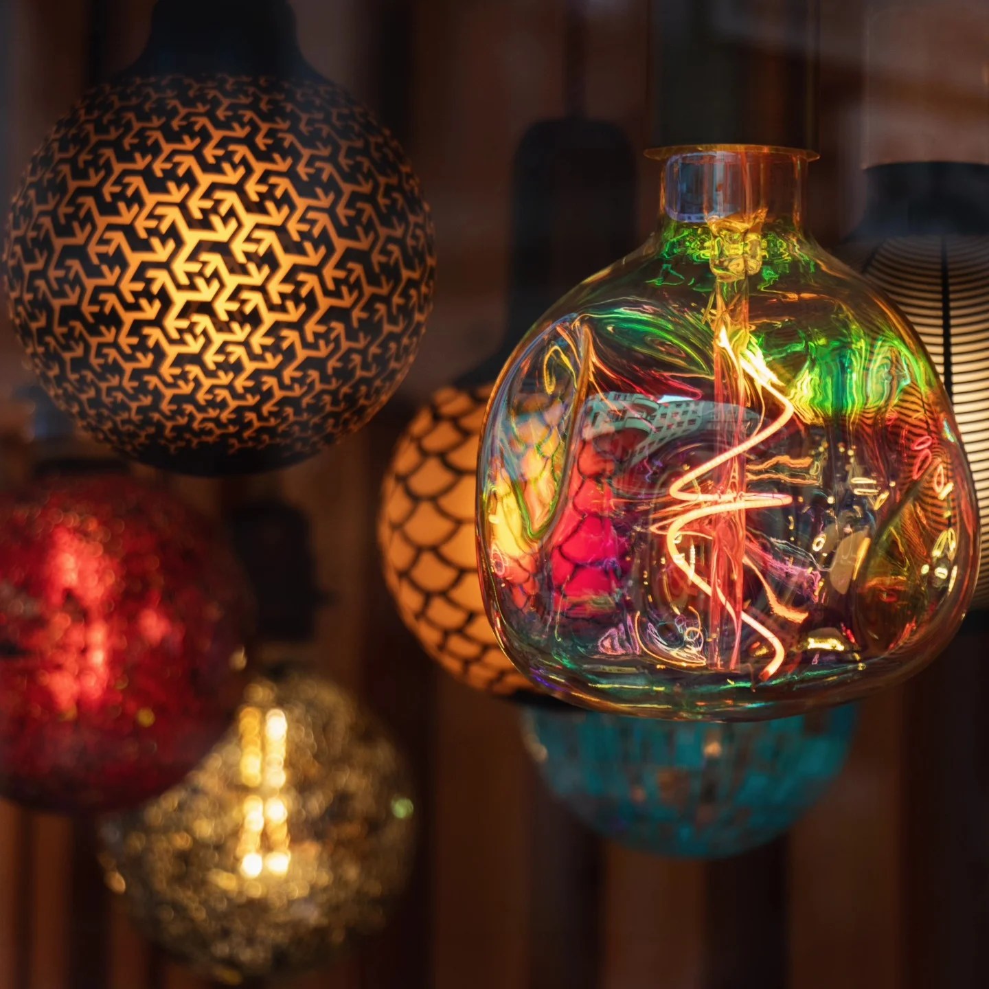 A close-up of multicolored glass lamps and light bulbs glowing warmly in a Porto shop window.