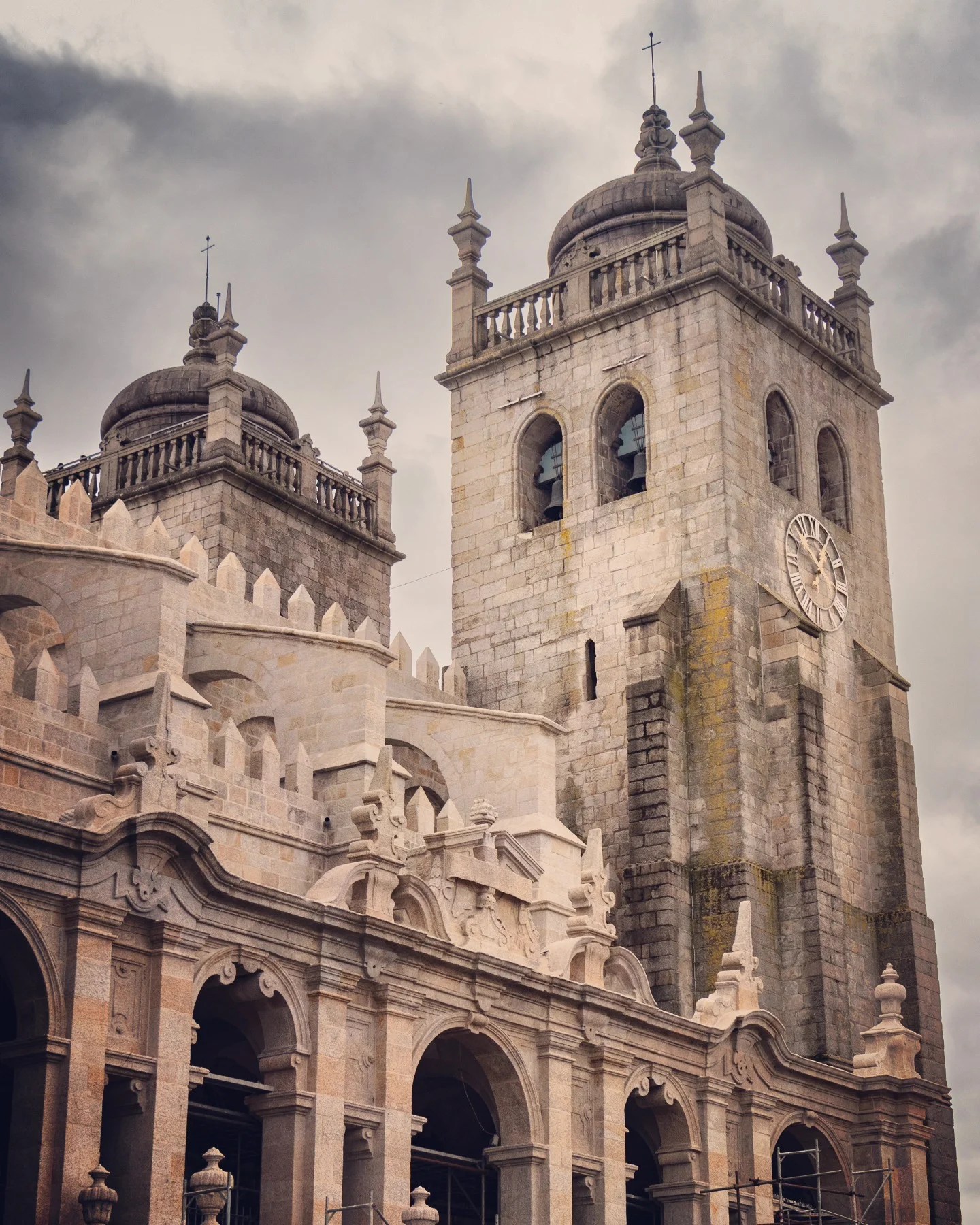Detailed view of one of the bell towers of Porto Cathedral (Sé do Porto), with Gothic and Romanesque stonework under a cloudy sky.