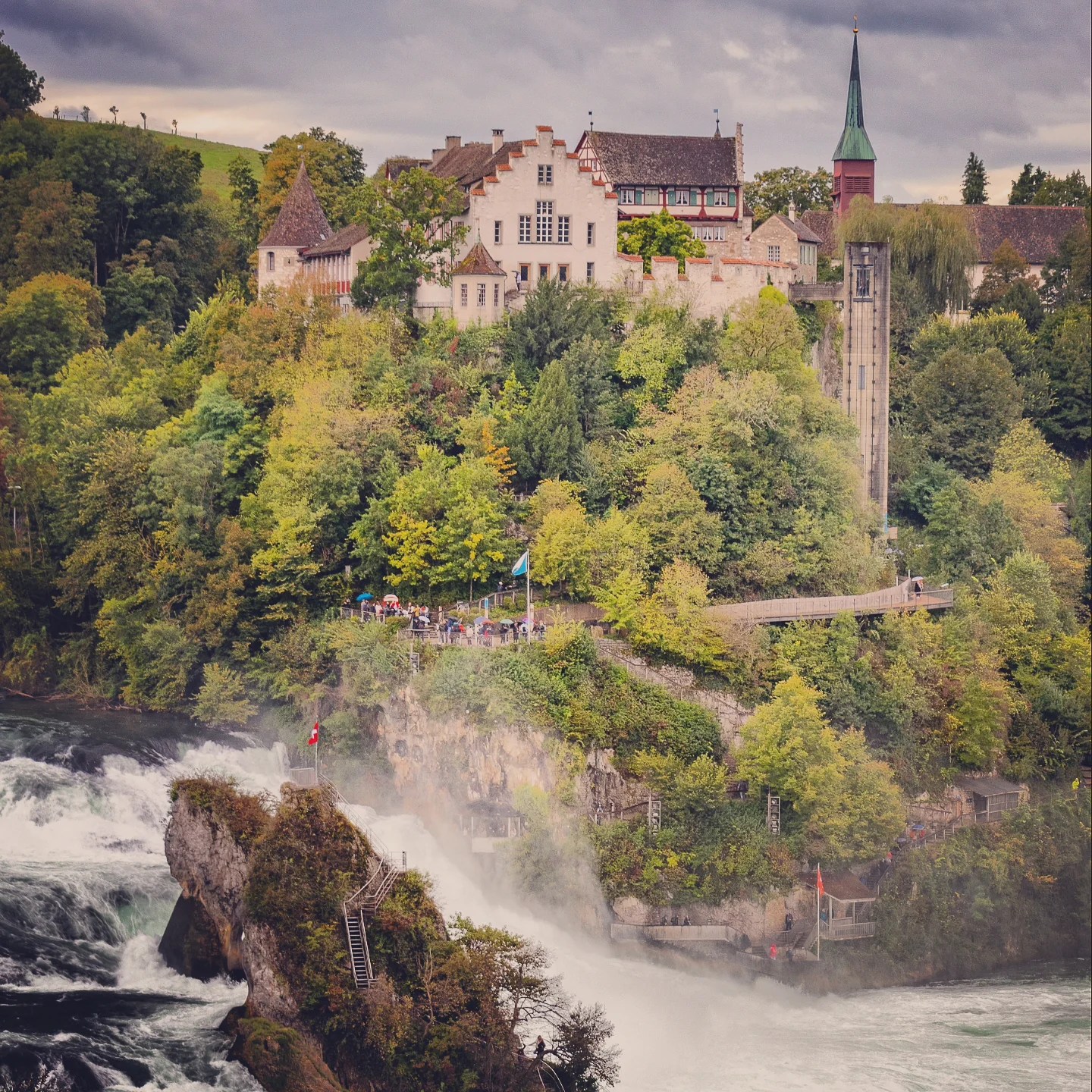 Schloss Laufen and cliff-side walkway rising over the spray of Rhine Falls.