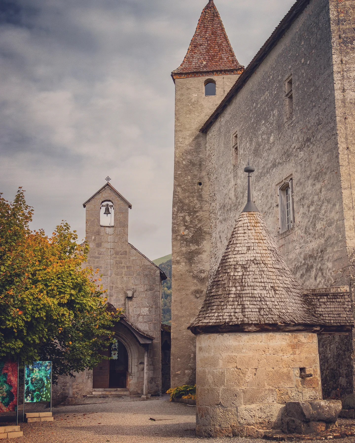 Inner court of Gruyères Castle showing a tall square tower, a tiny shingled well house and a chapel bell gable.