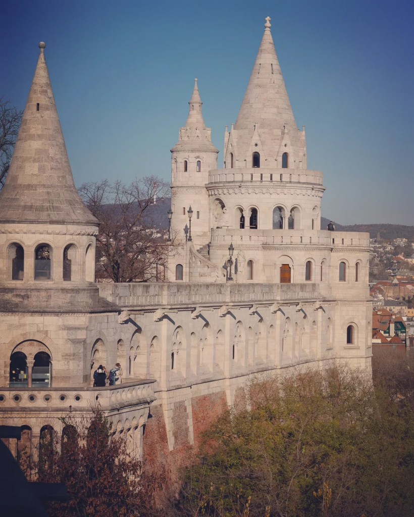 Side view of Fisherman’s Bastion with its arched walkways and conical turrets under a clear blue sky.