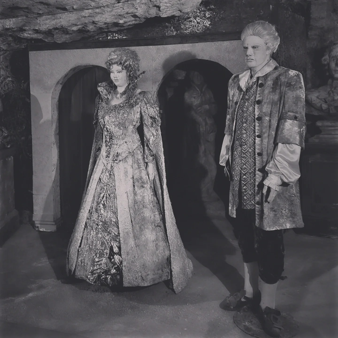 Wax figures in elaborate period costumes posed in a dimly lit stone room of the Labyrinth.