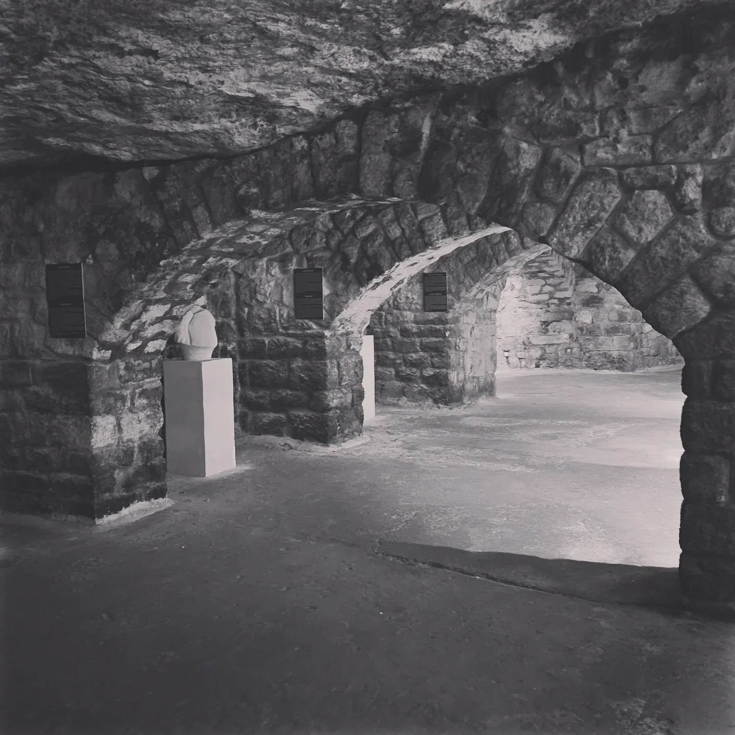 Stone arches inside the Labyrinth with sculptures on display in softly lit alcoves.