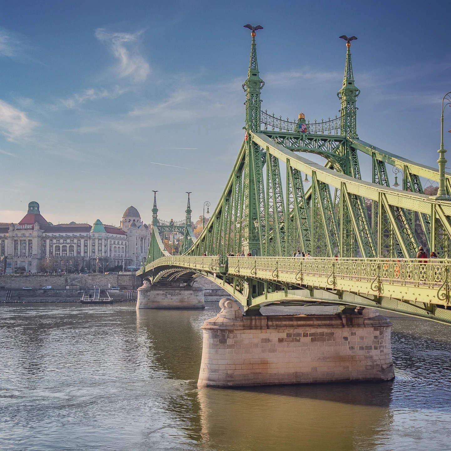 Liberty Bridge in Budapest spanning the Danube, with ornate green ironwork and eagle-topped spires