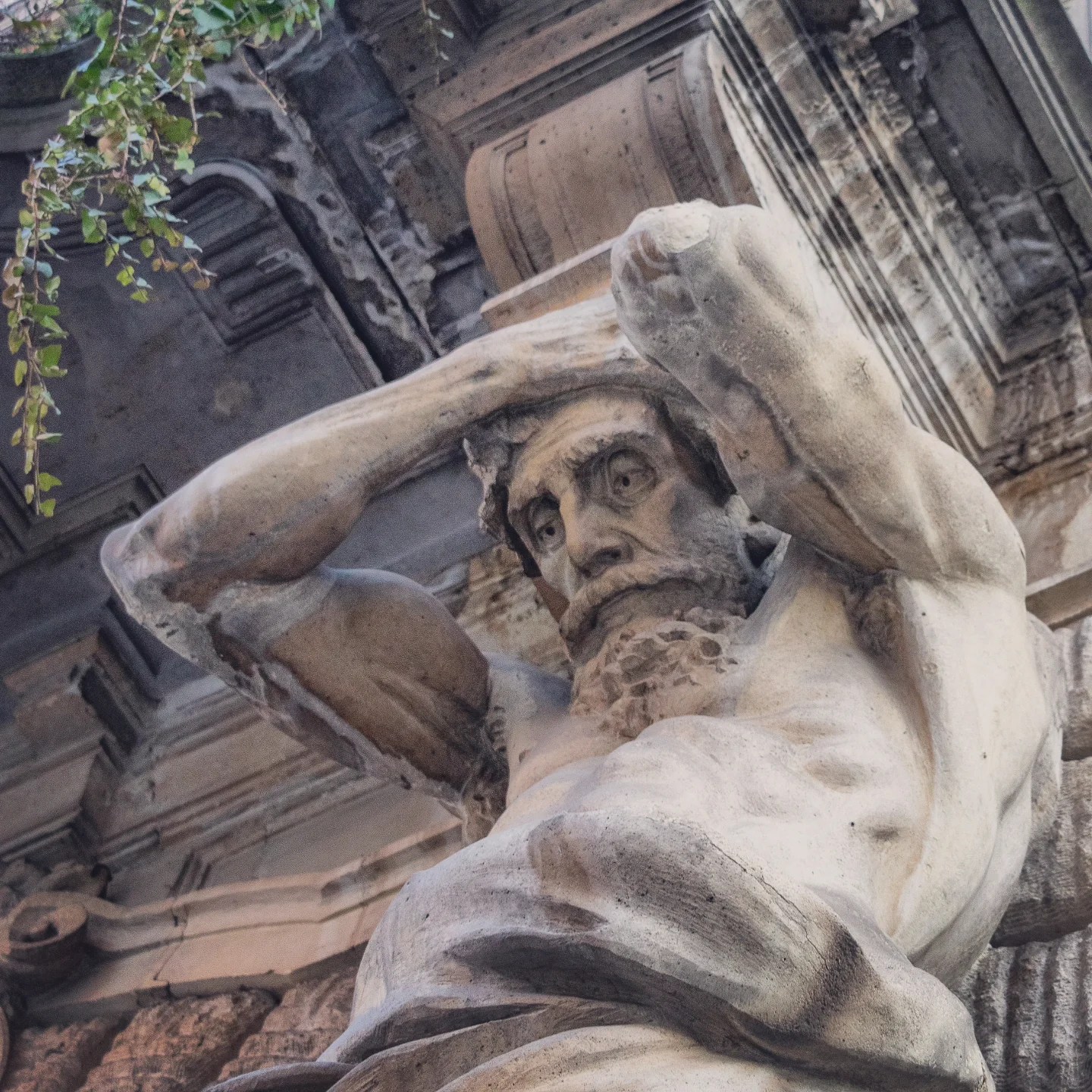 Dramatic stone statue of a muscular figure supporting an overhang in Budapest.