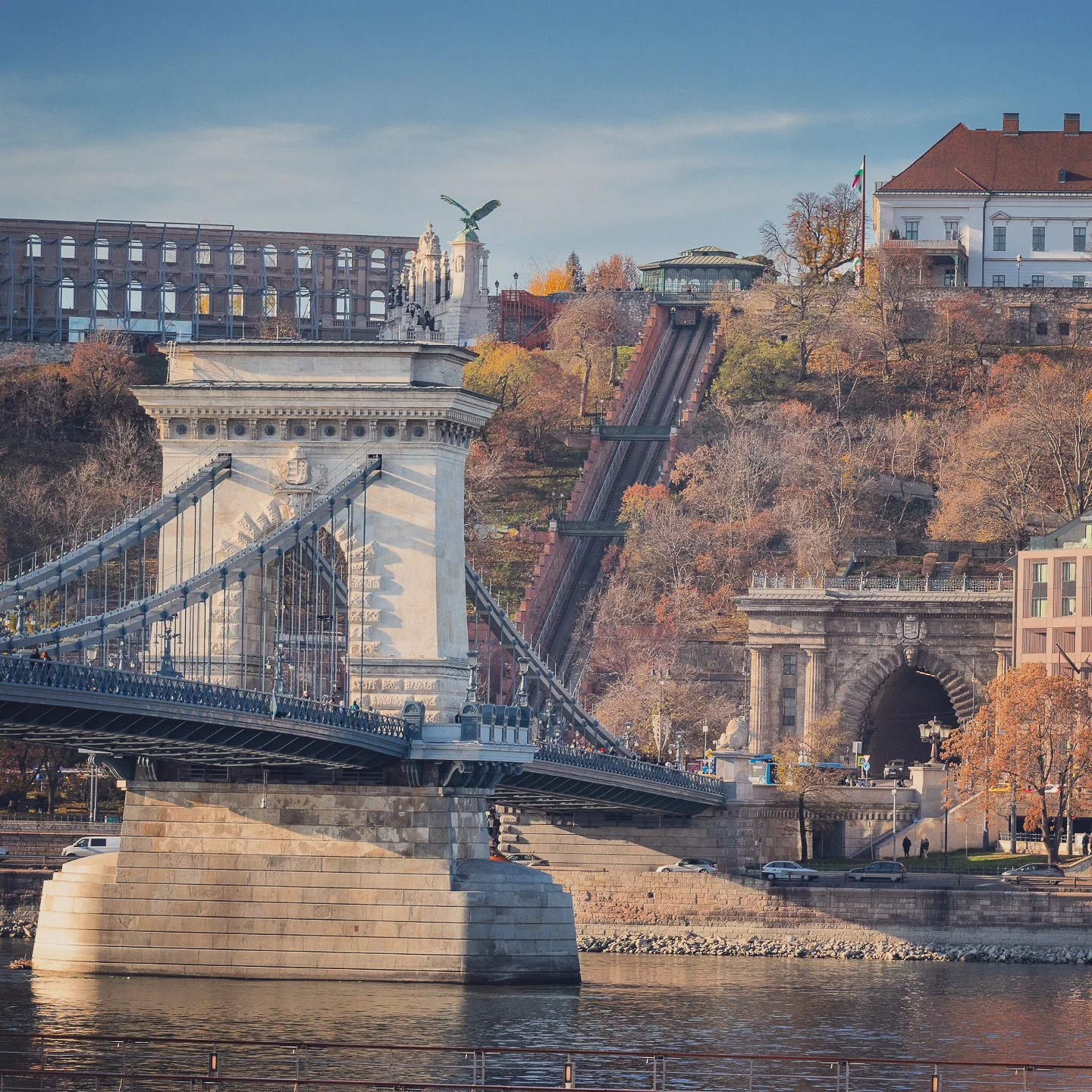 View of the Chain Bridge and the Budapest Castle Hill funicular in the background with autumn foliage.