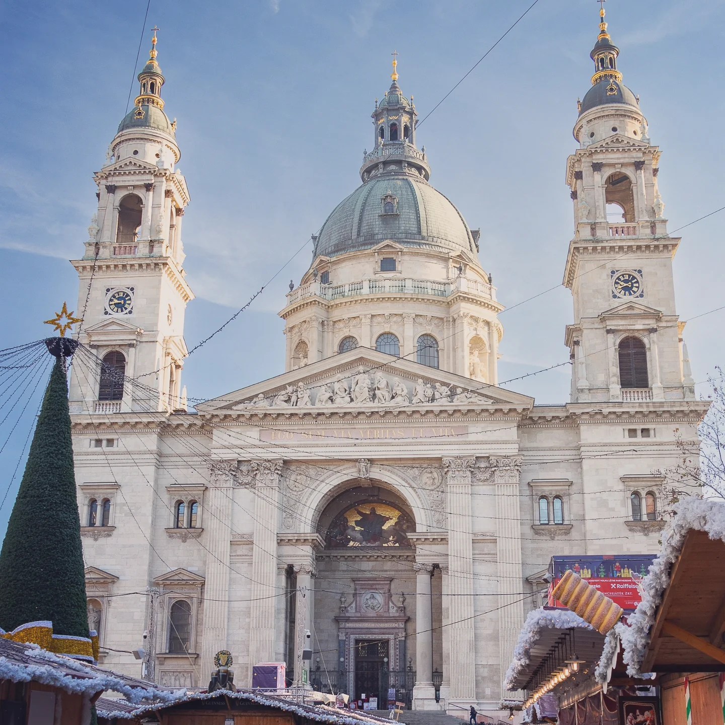 St. Stephen’s Basilica with Christmas market stalls and a decorated tree in front.