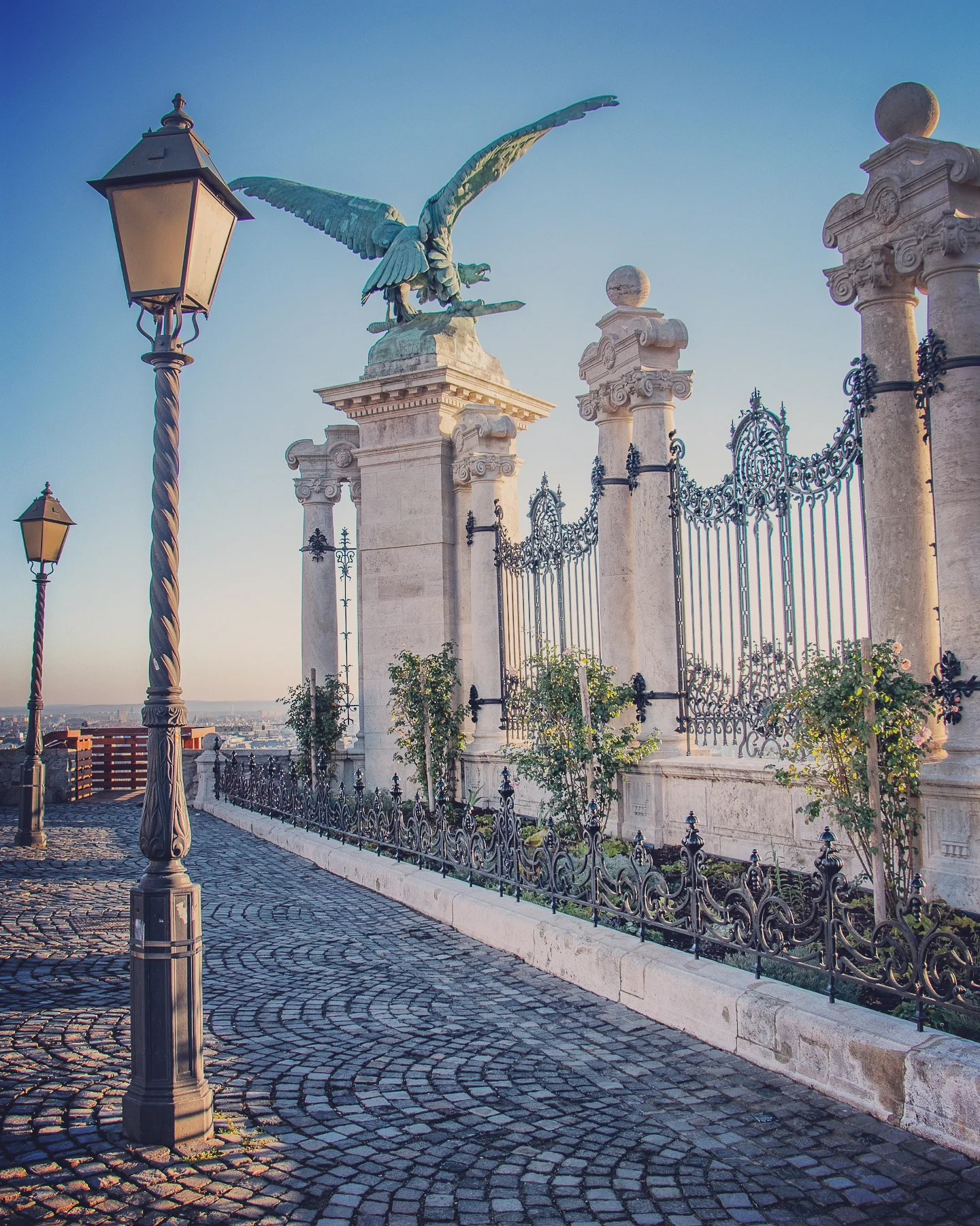 Stone eagle statue perched above ornate gates at Buda Castle in Budapest.