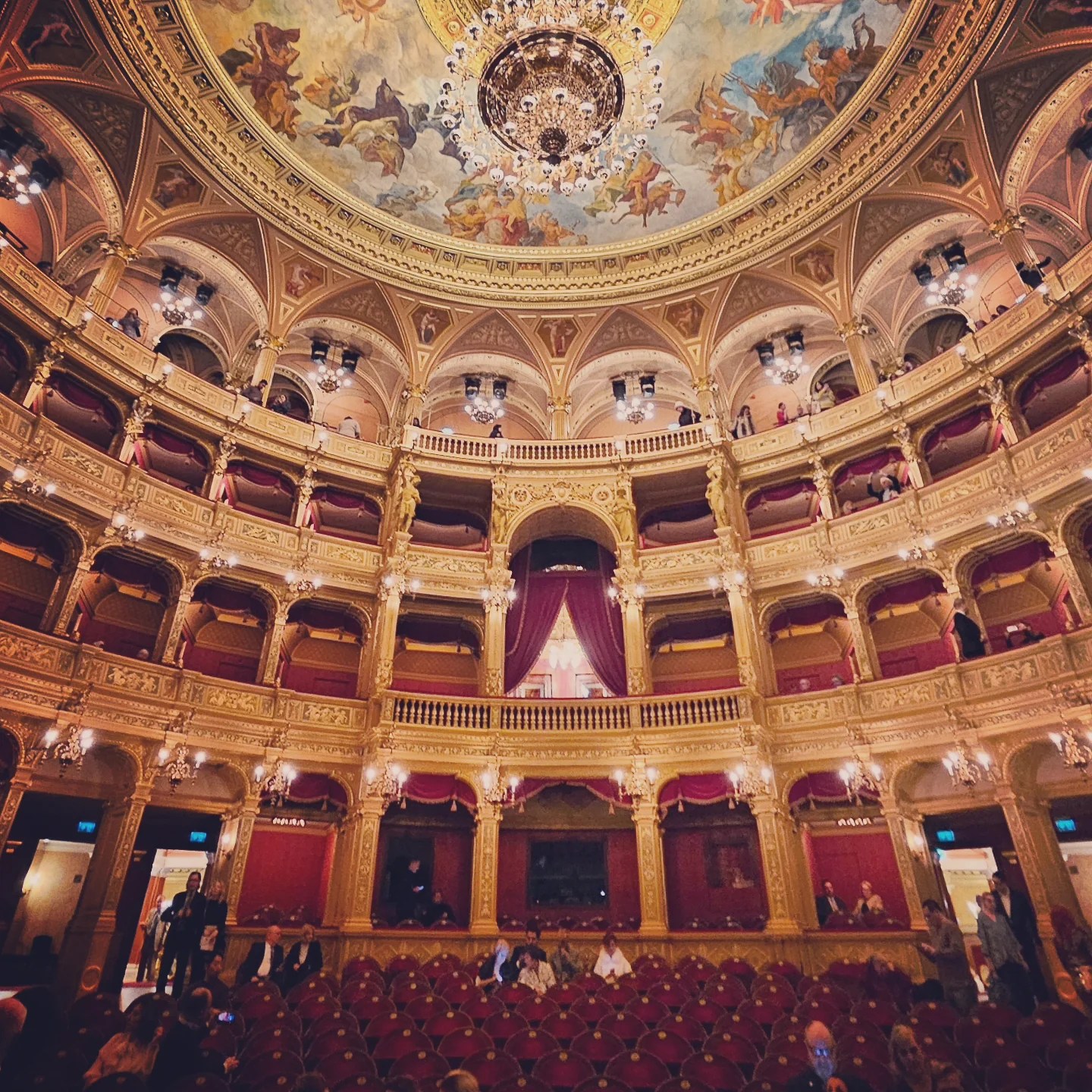 The interior dome and balconies of the opera house, with a frescoed ceiling and grand chandelier.