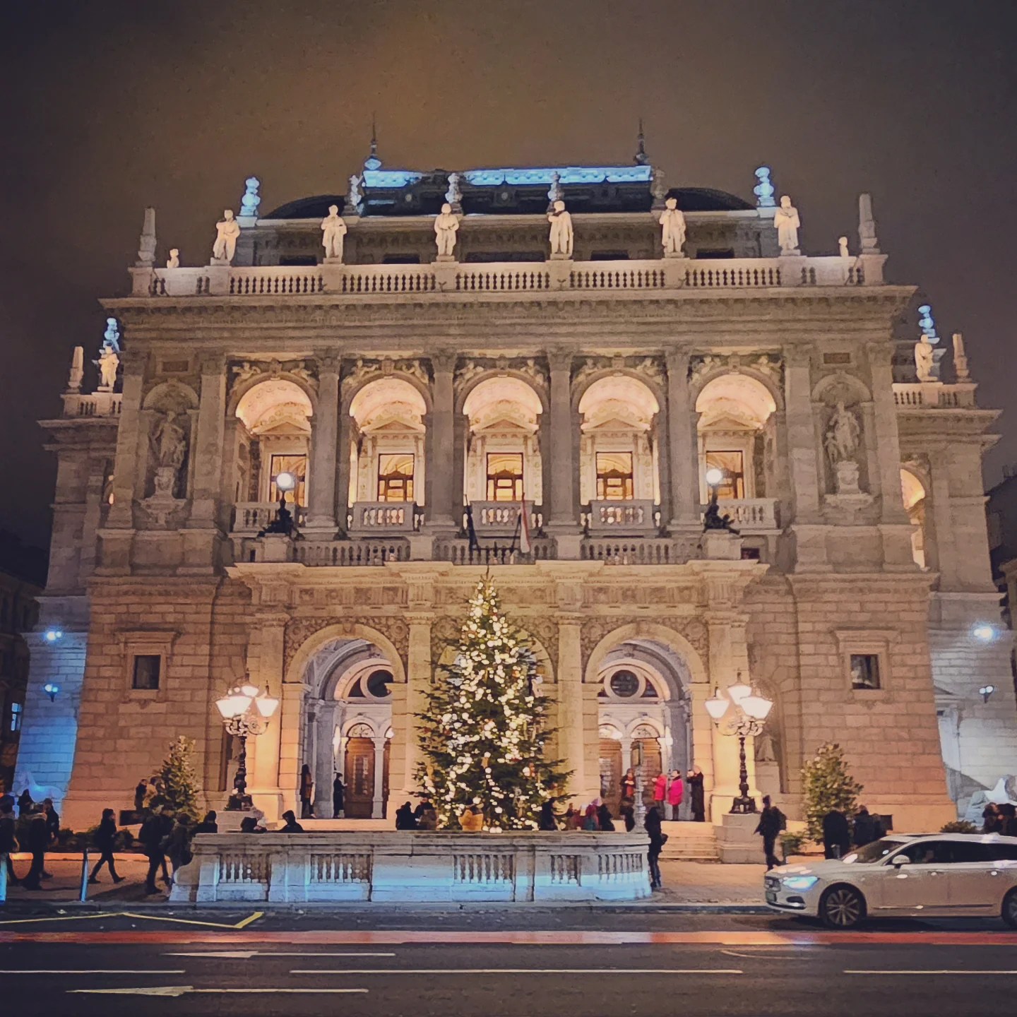Exterior of the Hungarian State Opera House at night, decorated with a lit Christmas tree.
