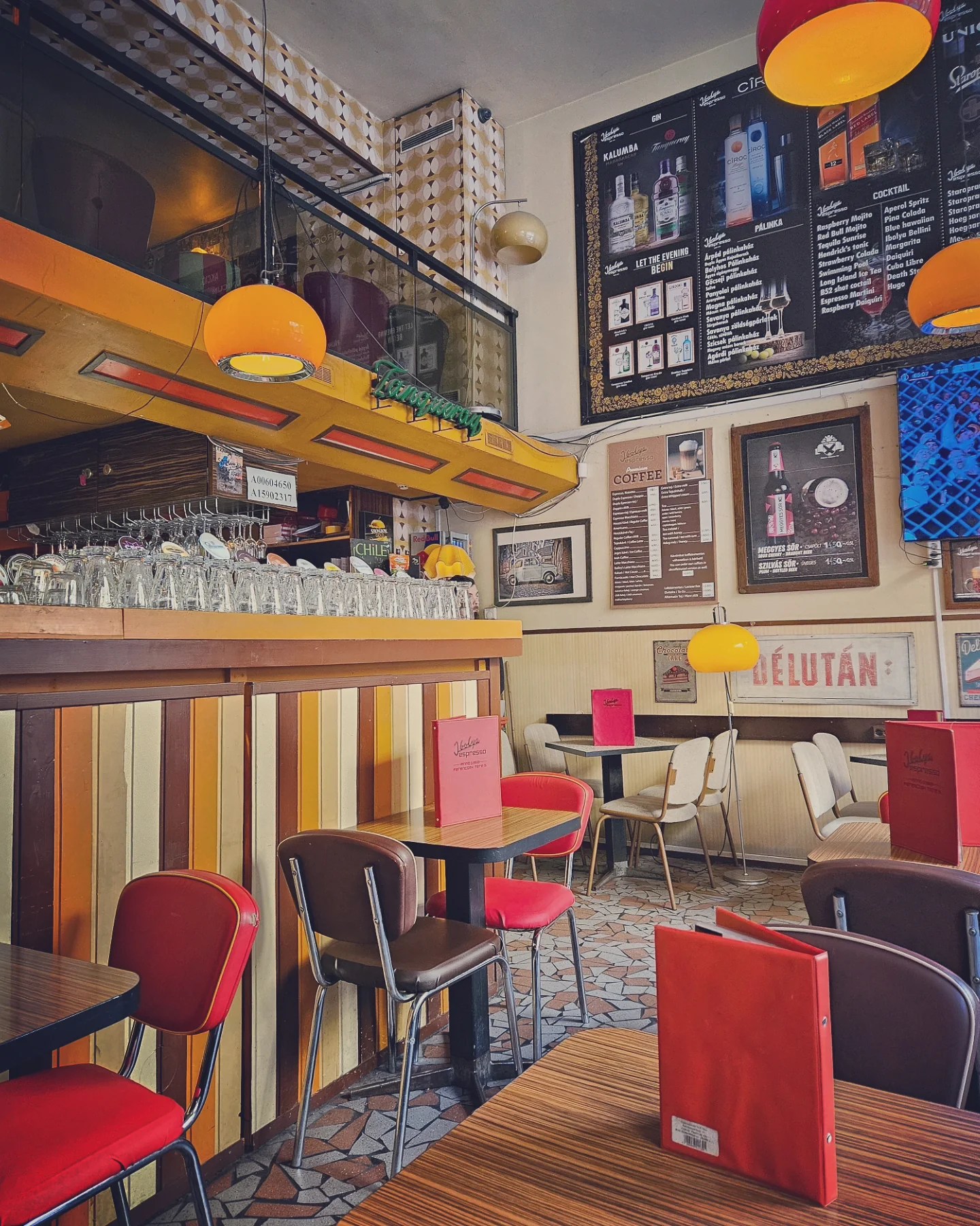 Interior of a retro café with bold colors, patterned tiles, and red menus on the tables.
