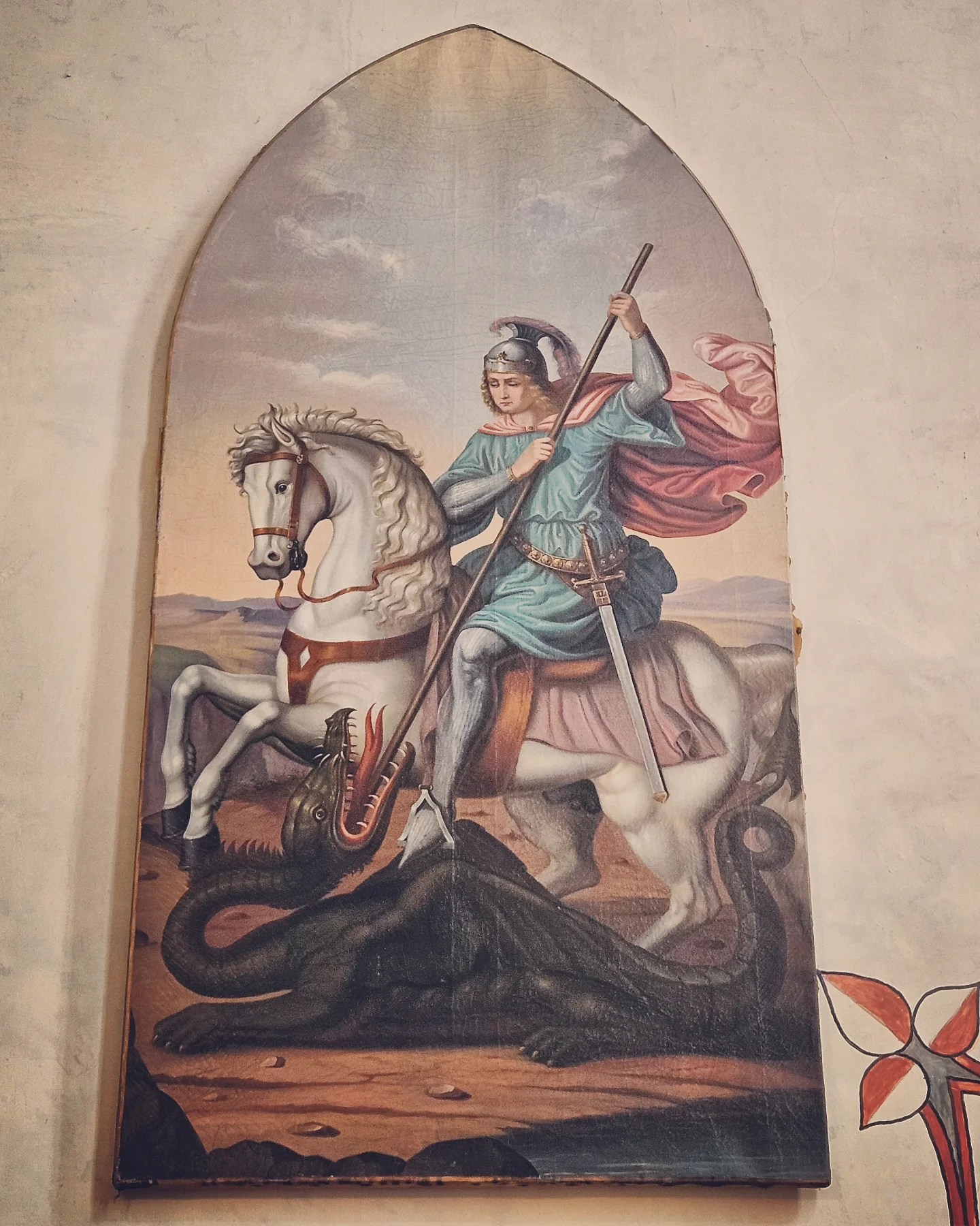A traditional religious painting of Saint George slaying a dragon, displayed on a church wall within Ljubljana Castle grounds.