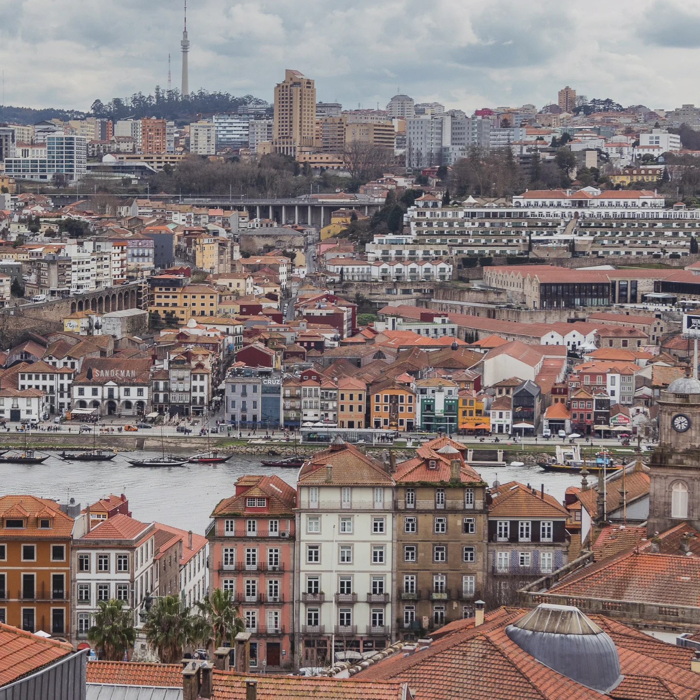 View across the Douro River from Porto, showing the colorful waterfront of Vila Nova de Gaia and distant city skyline.