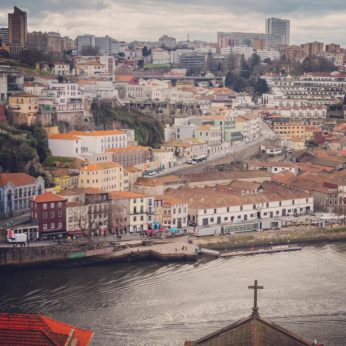 A panoramic view of Vila Nova de Gaia’s waterfront, with the famous CALEM wine lodge and colorful buildings along the Douro River.