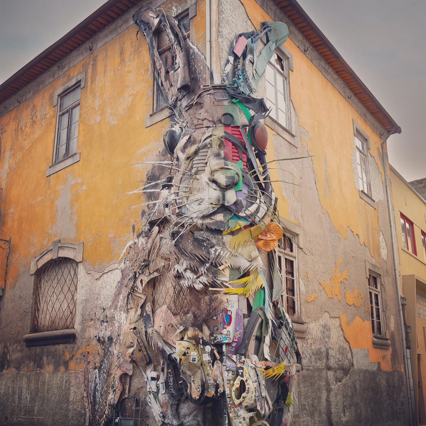 Giant rabbit street art installation made from recycled materials on a yellow building in Gaia.