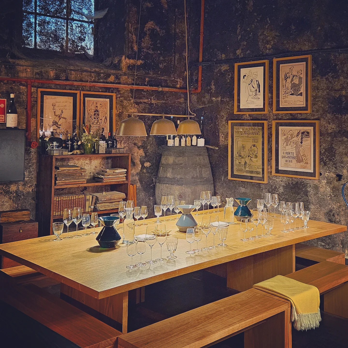 Cozy interior of a Porto wine tasting room with wooden tables set with dozens of wine glasses ready for tasting.