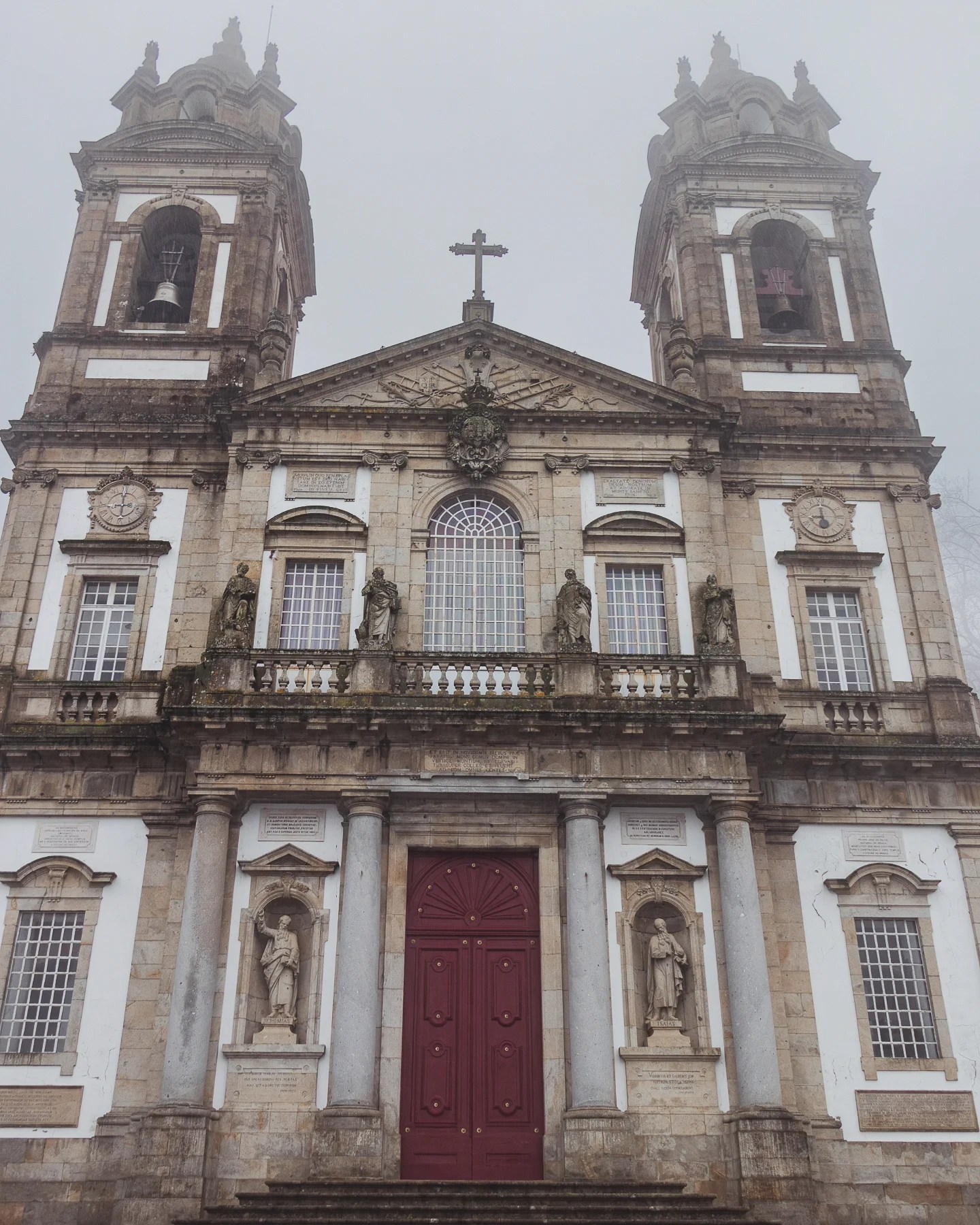 Close-up view of Bom Jesus do Monte façade showing statues, stone columns, and the iconic red door in Braga, Portugal.