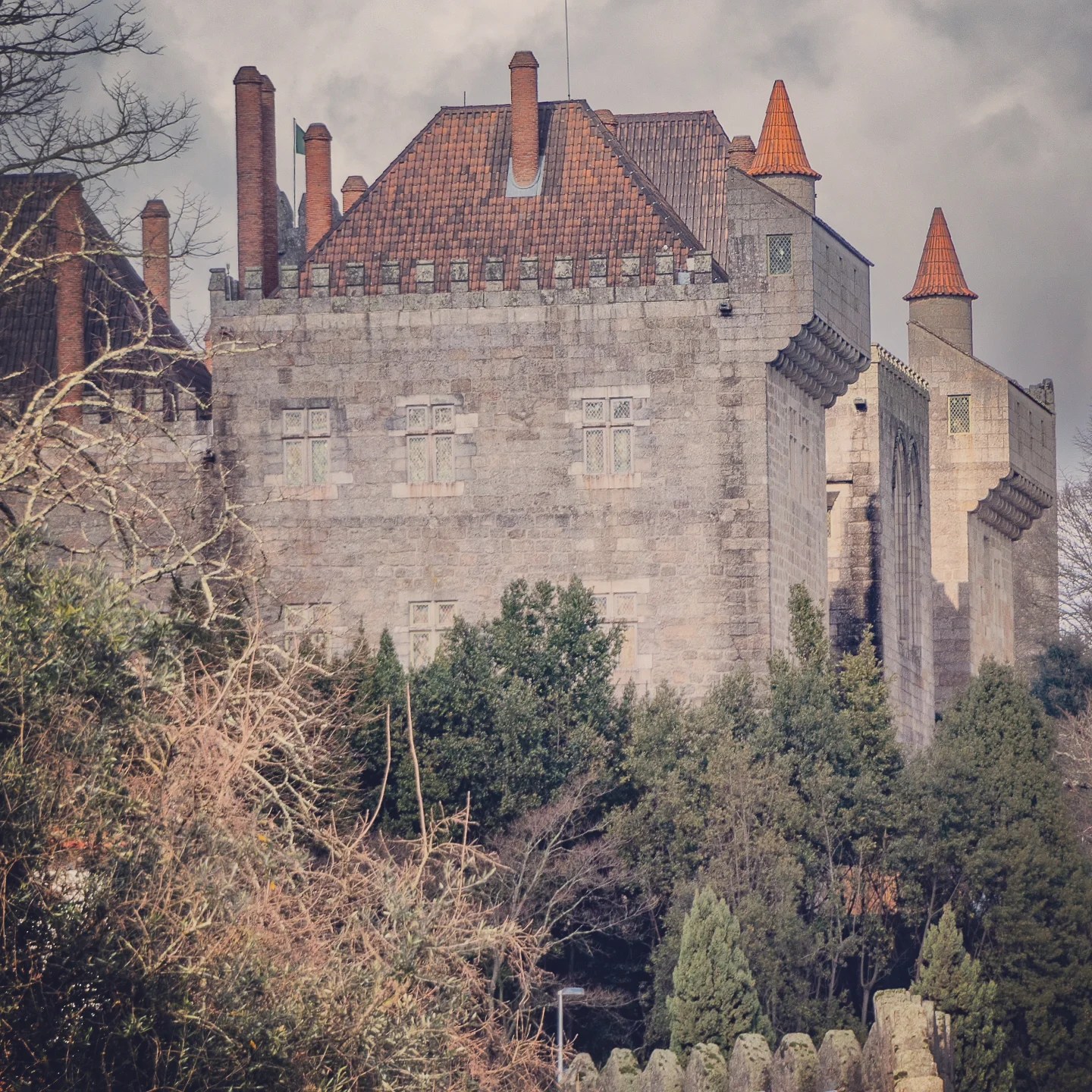 Distant view of the Palace of the Dukes of Braganza (Paço dos Duques de Bragança) with tall brick chimneys and stone walls in Guimarães, Portugal.