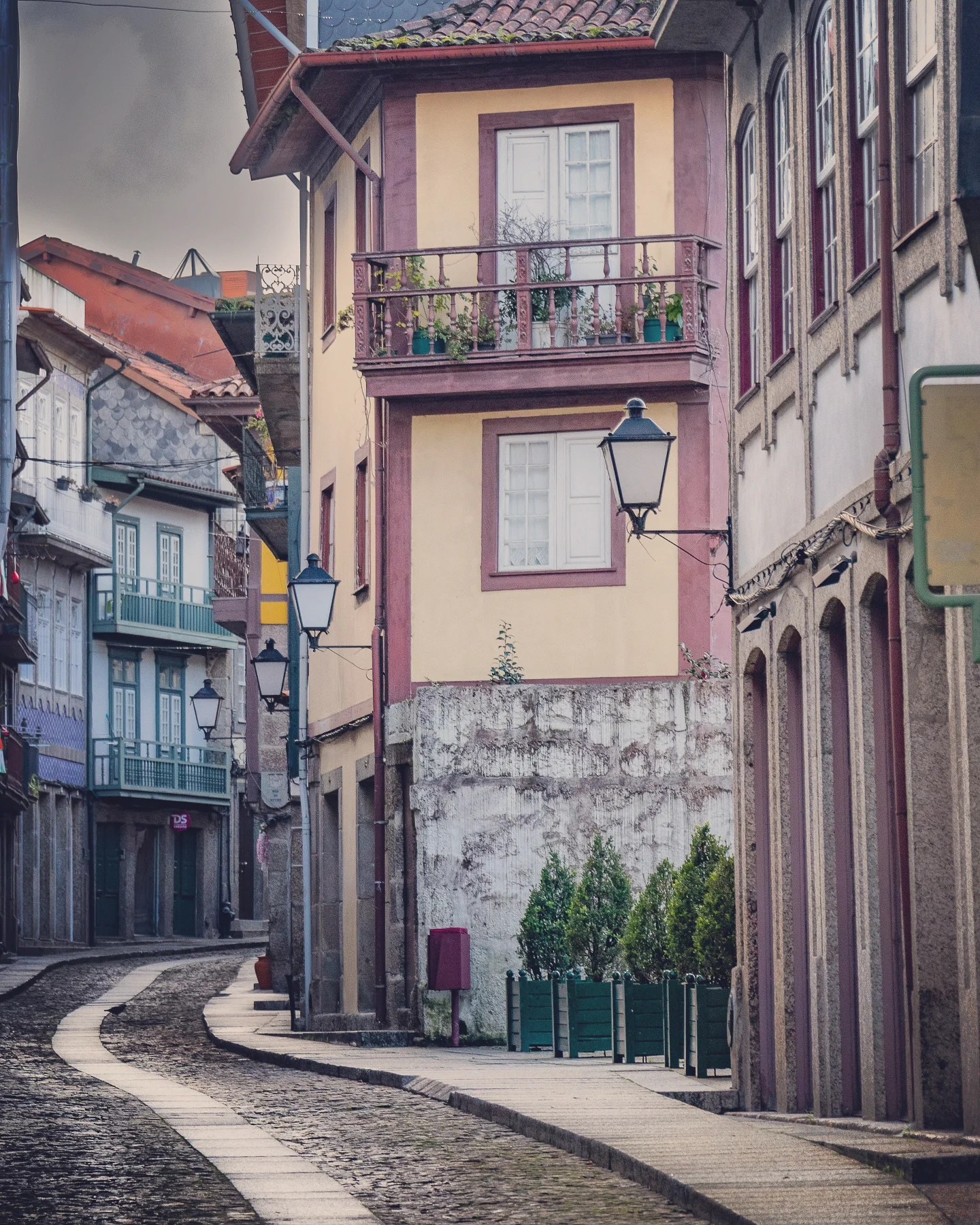 Narrow cobblestone street with colorful houses and balconies in the historic center of Guimarães, Portugal.