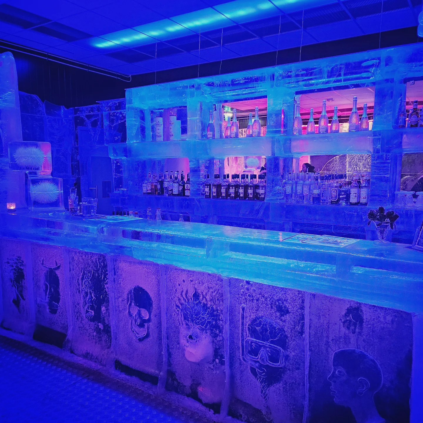 A surreal, glowing-blue bar made entirely of ice, with shelves of bottles and Arctic-themed engravings carved into the counter.