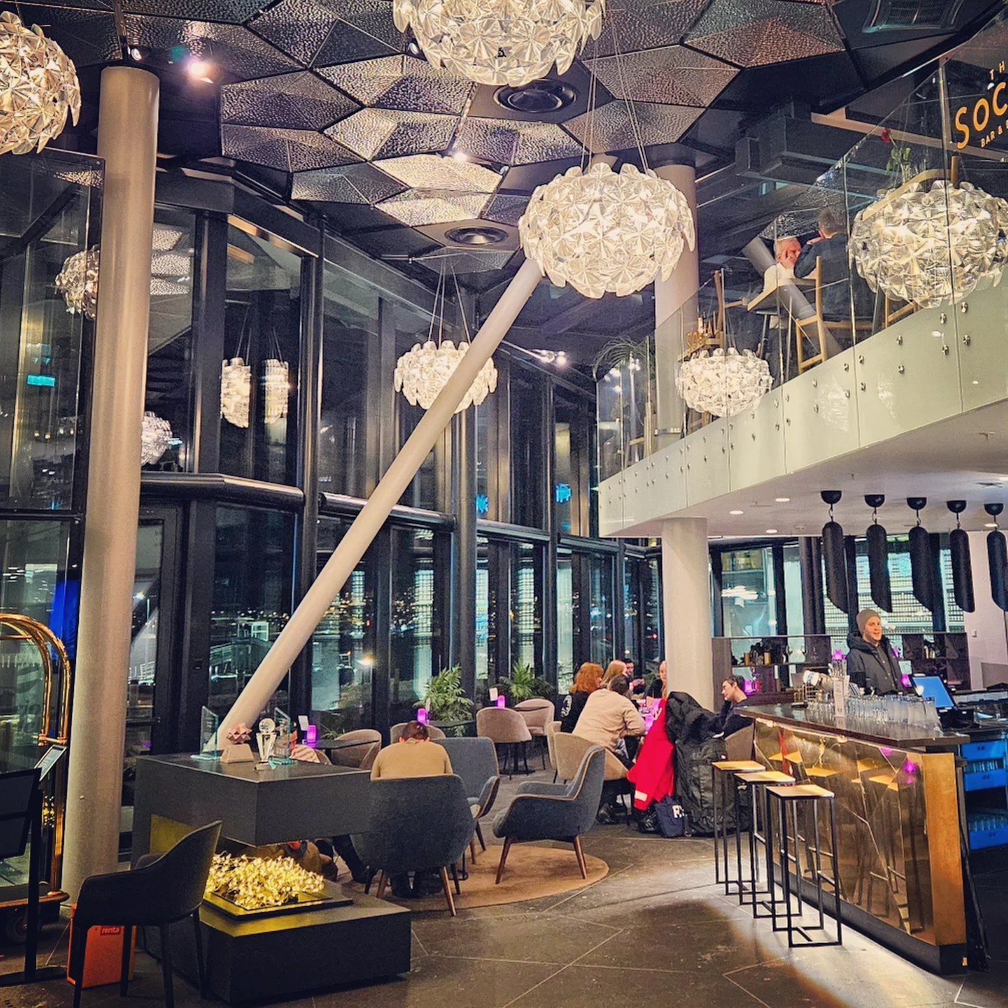 Chic modern lounge area with crystal chandeliers and sleek bar seating, warmly lit against the dark Arctic night.