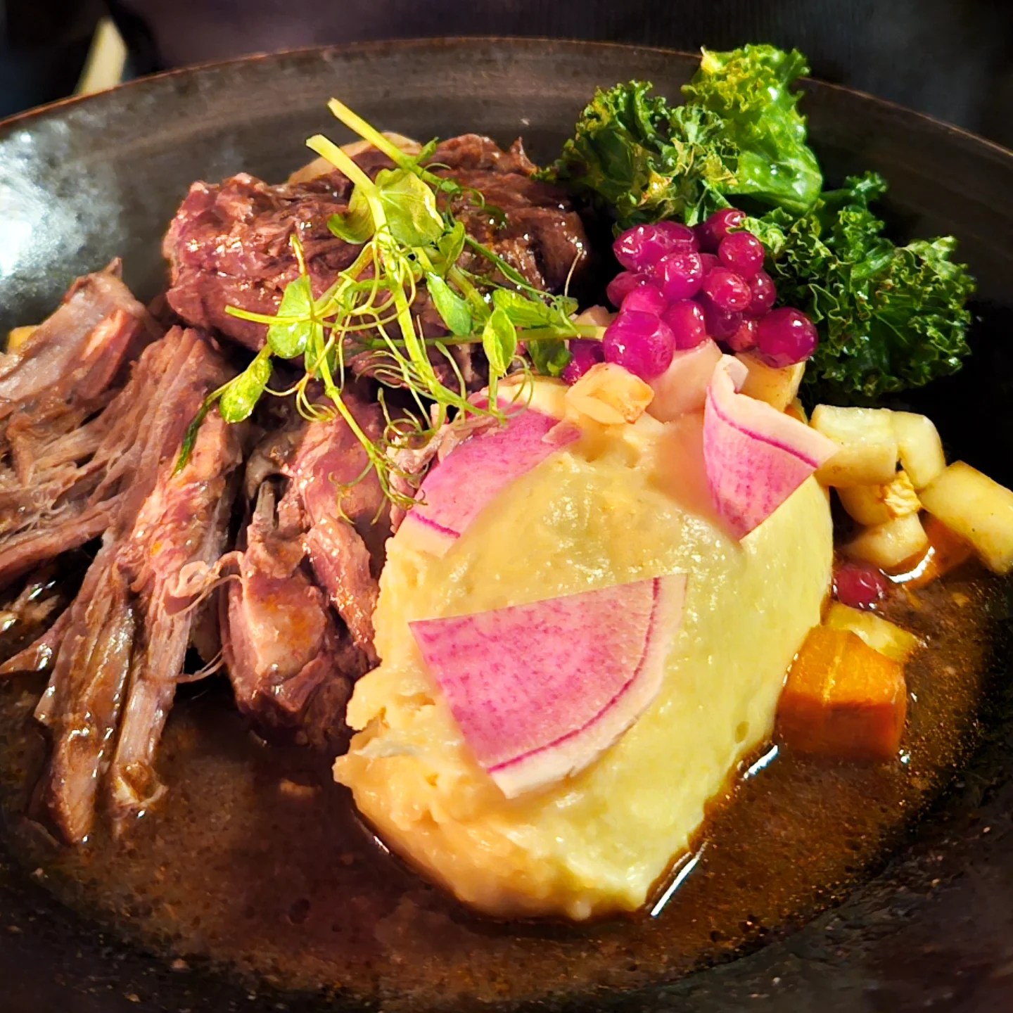 Tender reindeer served with mashed root vegetables, red berries, and artistic pink radish slices—Nordic comfort food on a plate.