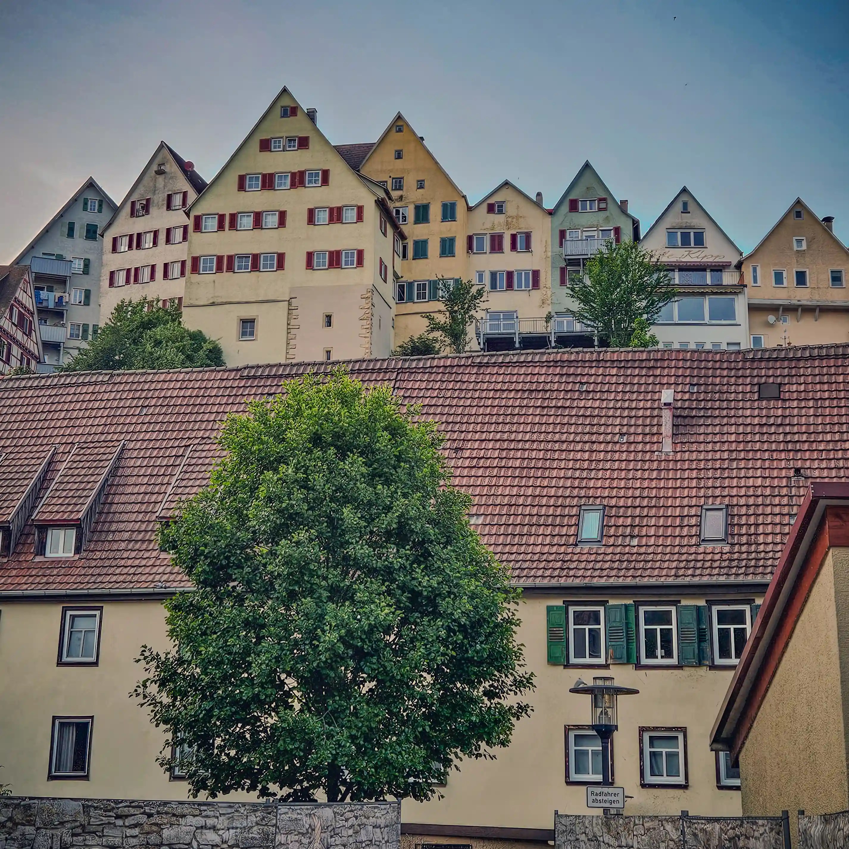 Traditional gabled houses in Horb am Neckar stacked on a hill, with geometric windows and red shutters catching the evening light.