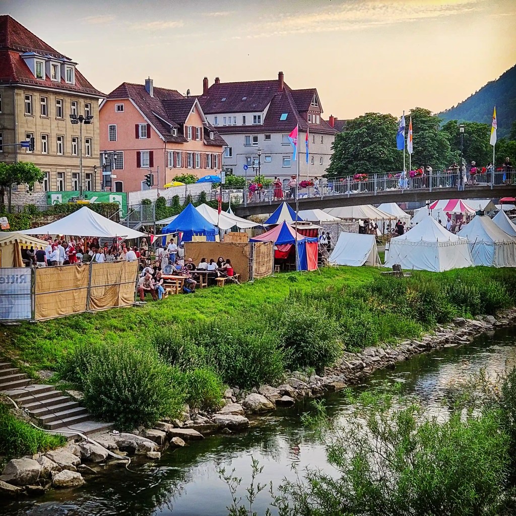 Colorful medieval tents and crowds along the riverside at Horb’s Knights’ Games, with the Neckar in the foreground and town buildings behind.