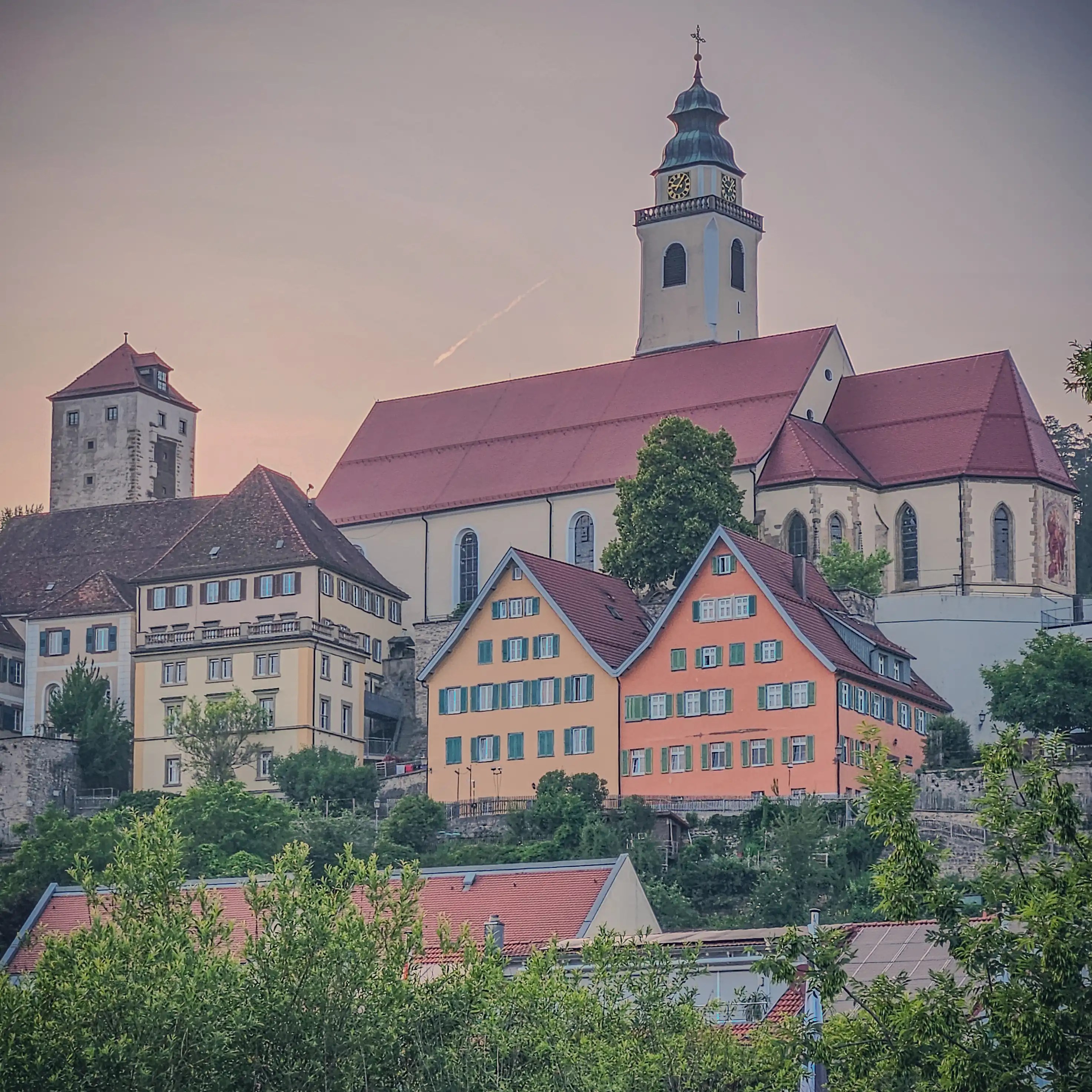 Close-up of Horb’s prominent church and colorful hillside buildings against a pink-tinted sky at dusk.