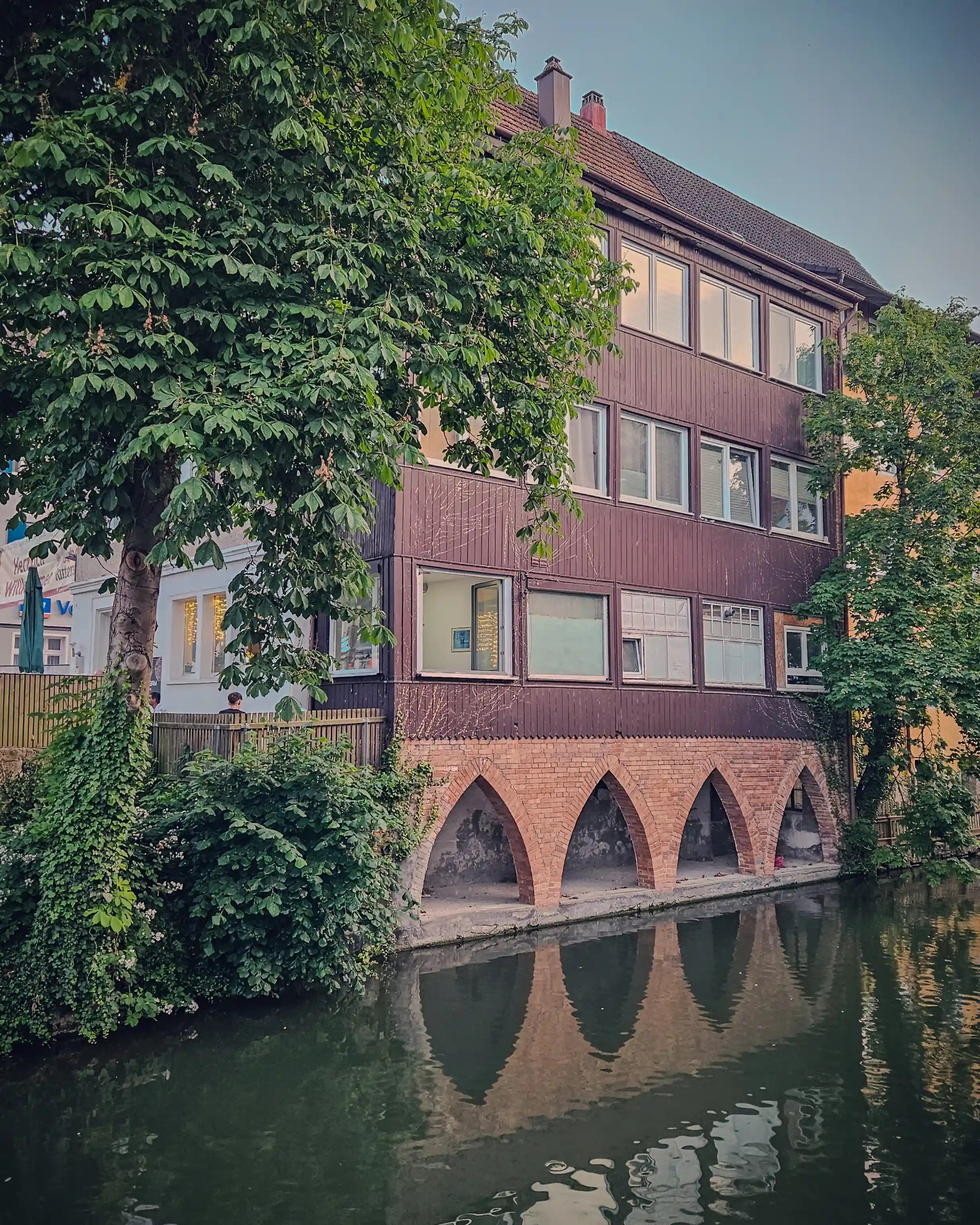 A brown wooden building with pointed brick arches sits directly above the water in Horb am Neckar.