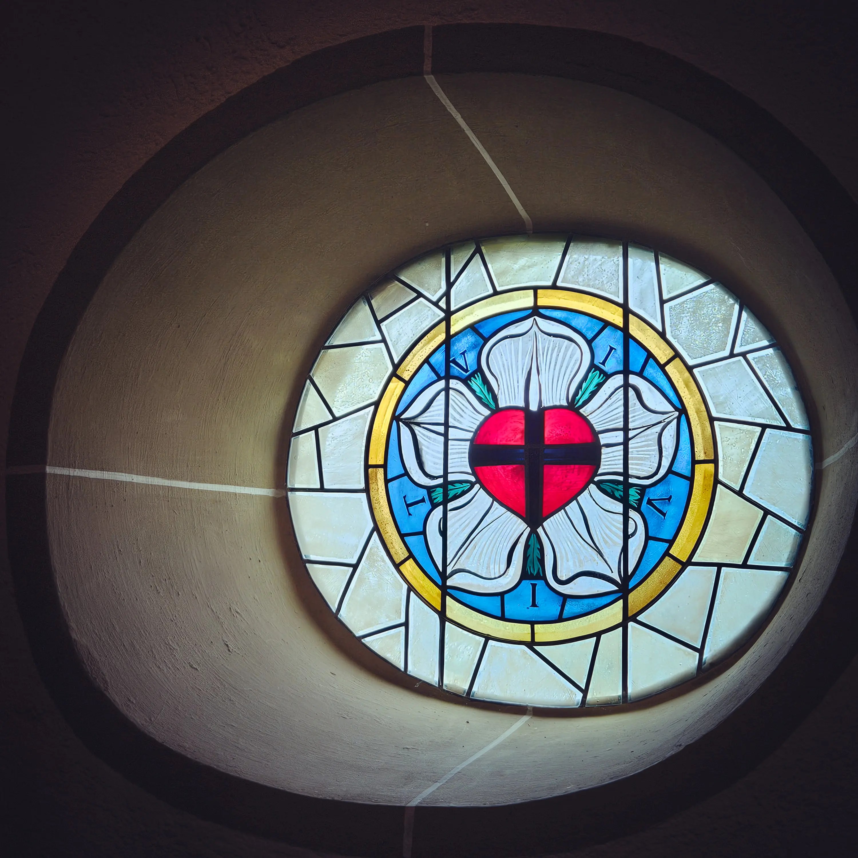 Stained glass window with Luther rose design inside Sebastianskirche, Bad Friedrichshall, Germany.