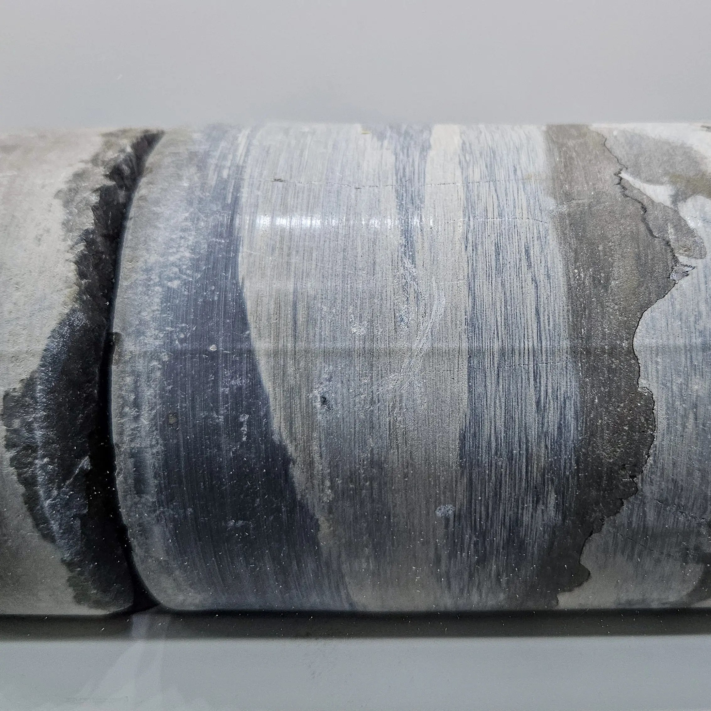 Cylindrical core sample showing distinct blue, gray and white mineral layers from the Bad Friedrichshall salt mine.