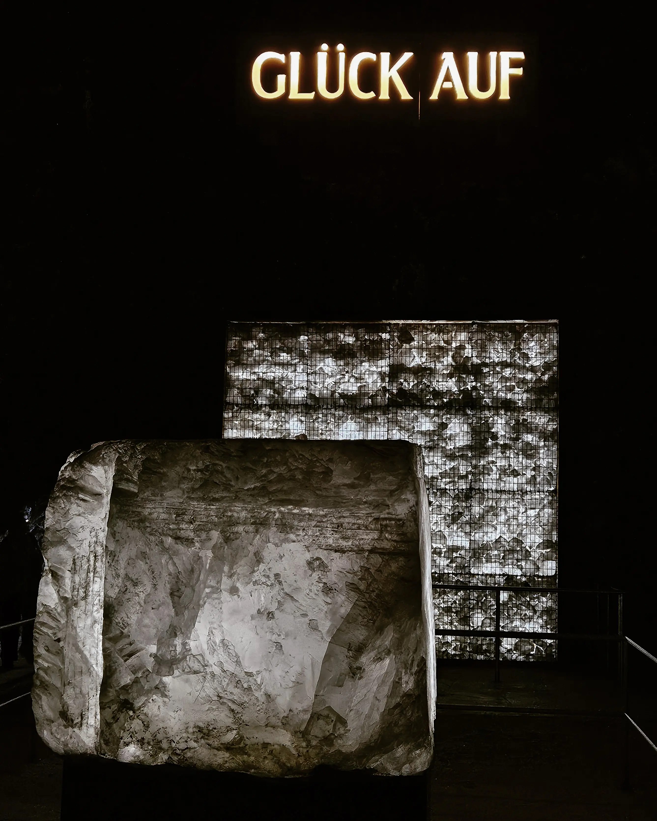 Massive illuminated salt block beneath the glowing “Glück Auf” miners’ greeting inside the Bad Friedrichshall salt mine.