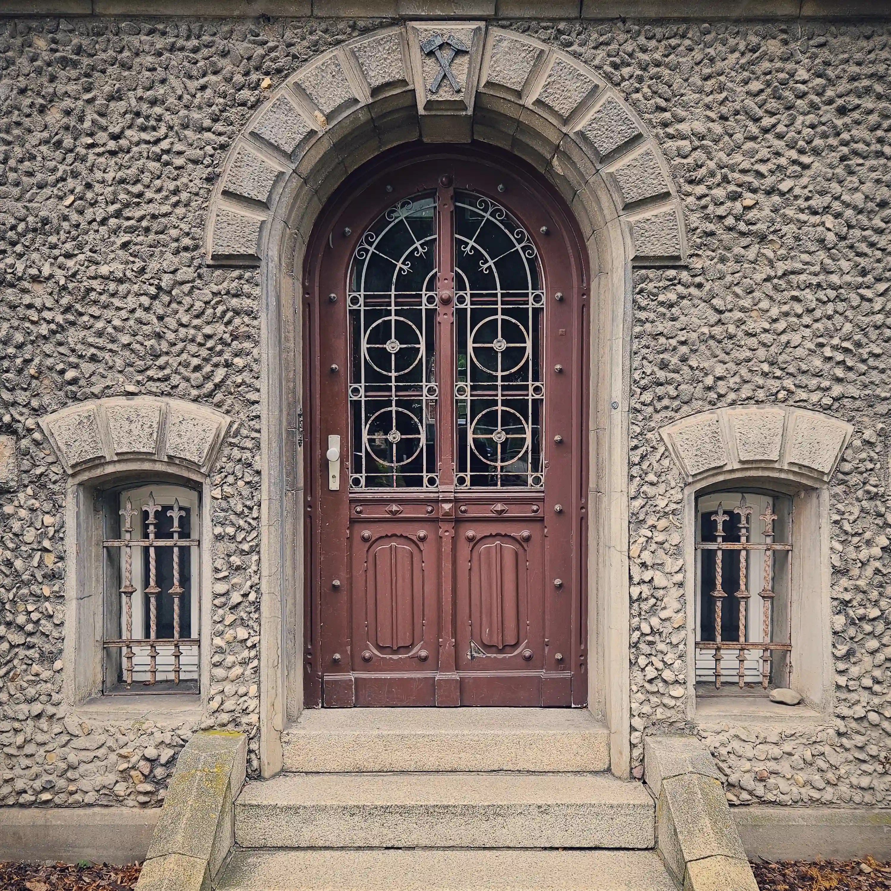 Decorative wooden door framed by stone with mining symbols above, in Bad Friedrichshall.