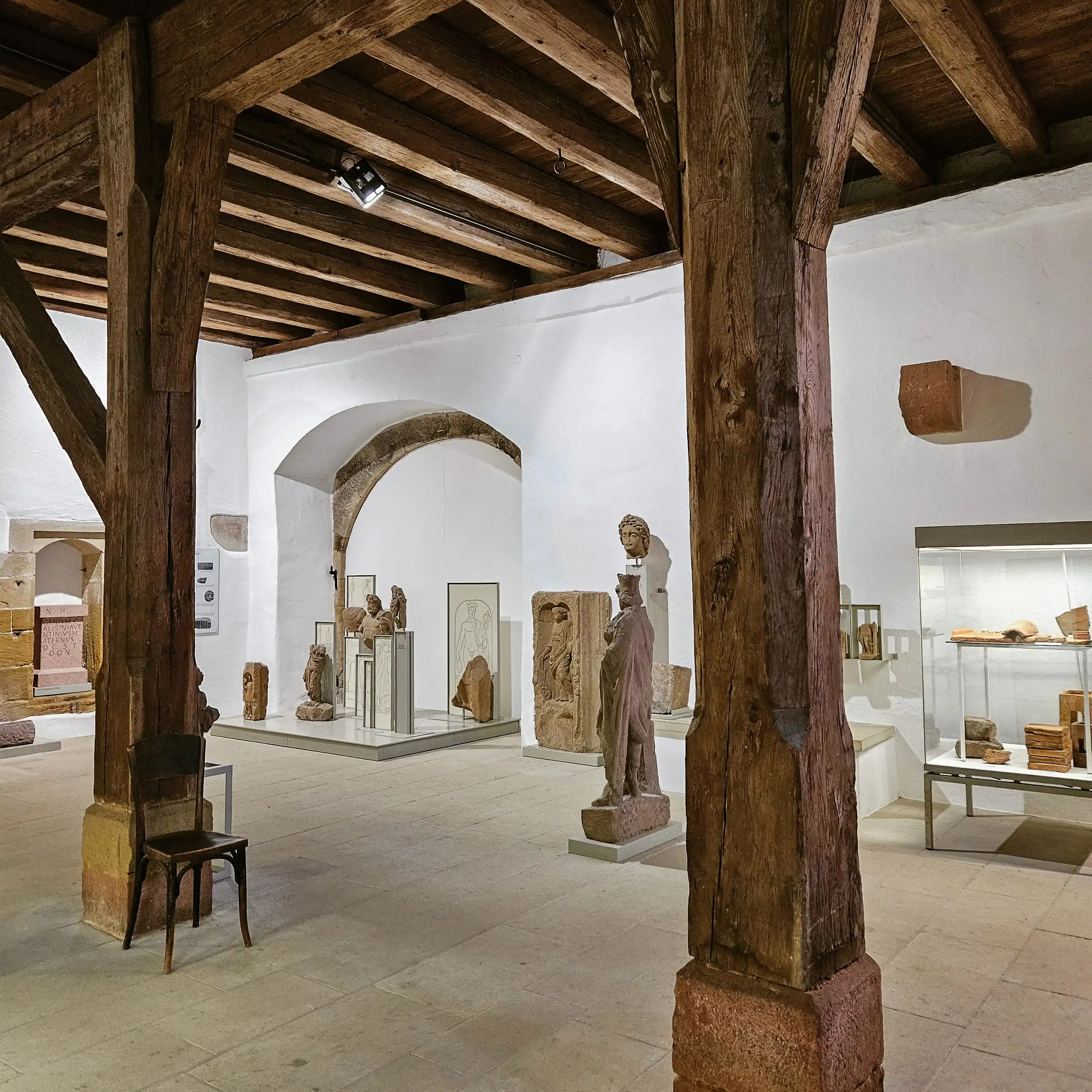 Exhibit hall with heavy timber beams and stone sculpture in Bad Wimpfen.