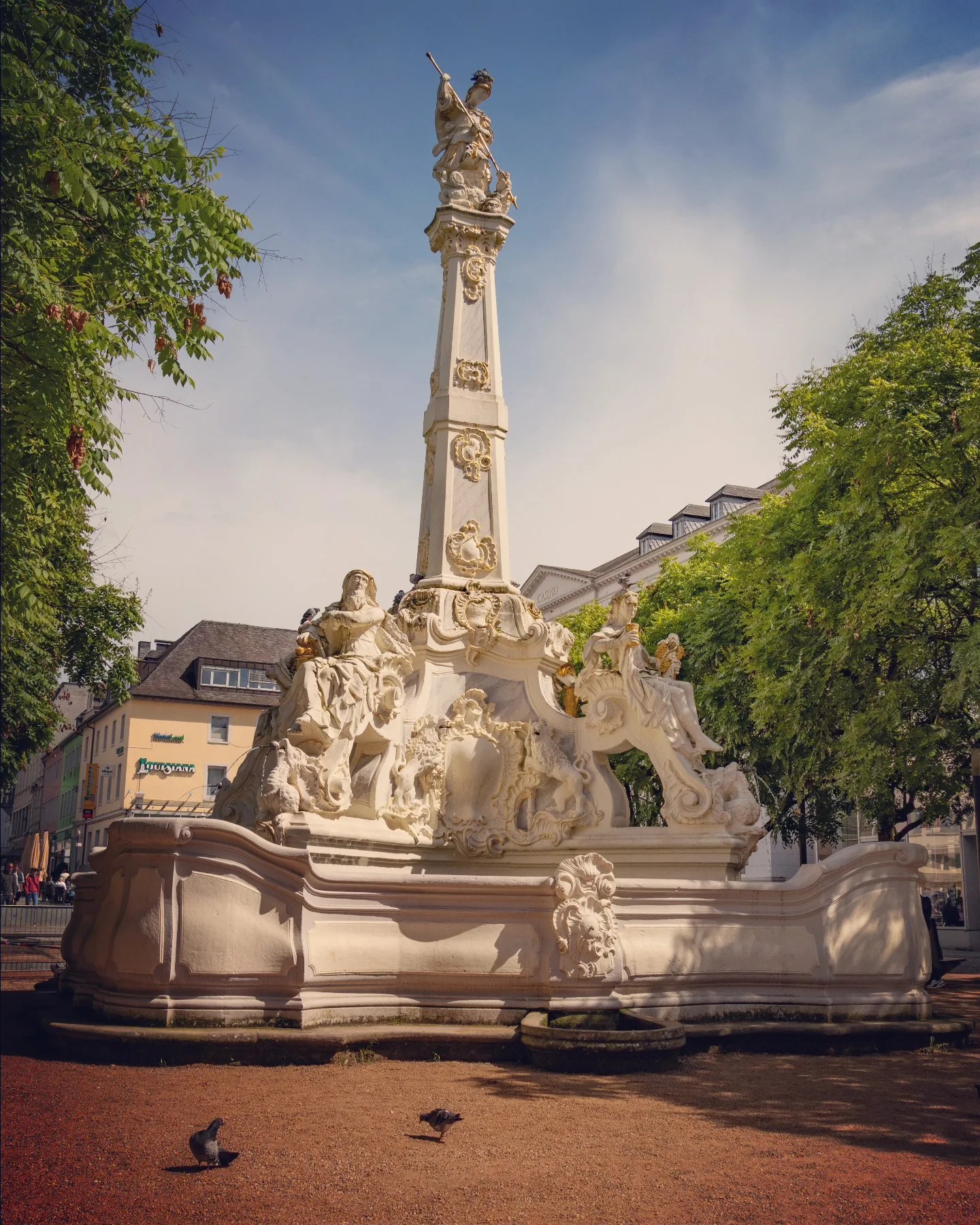 Rococo fountain with elaborate statues in Trier’s Kornmarkt, Germany.