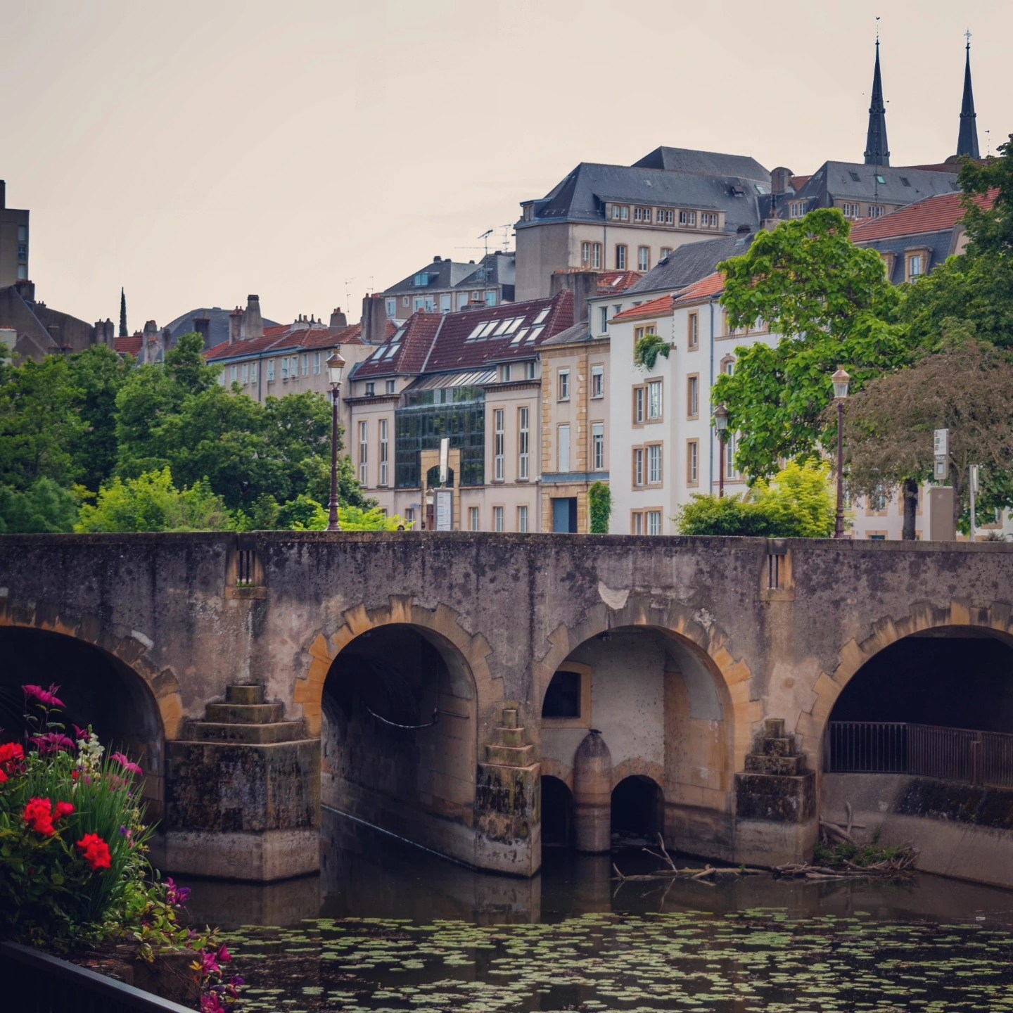 Stone bridge over the Moselle River with Metz buildings in the background.