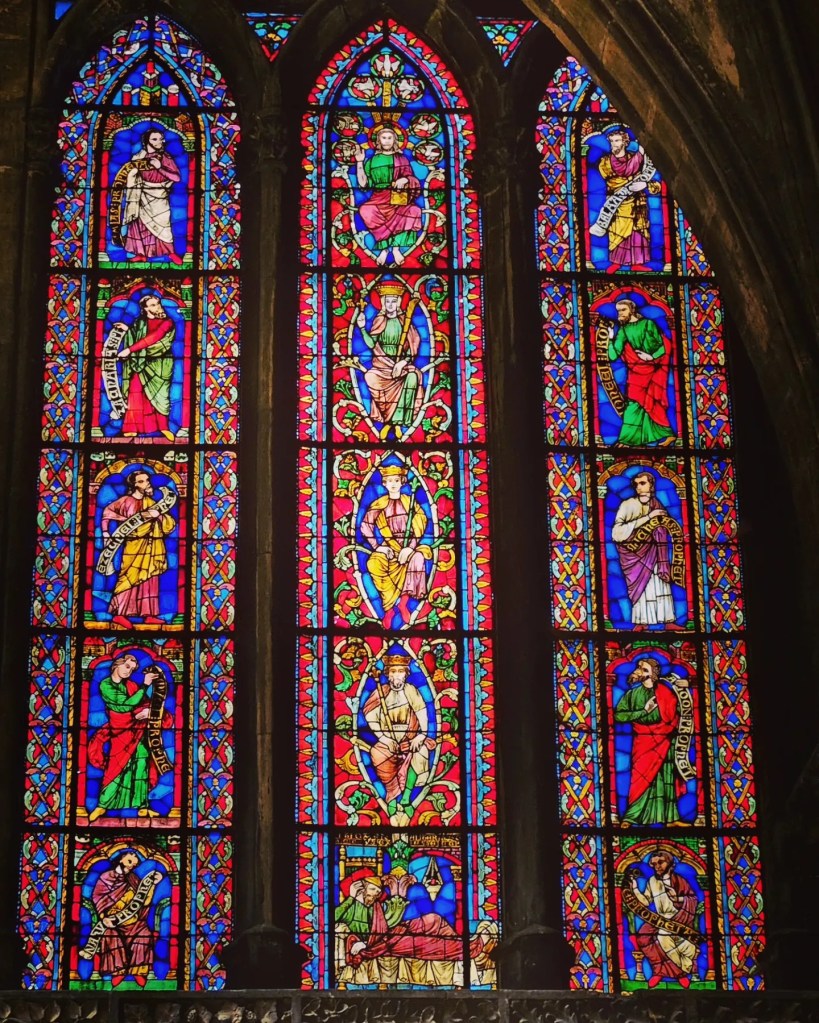 Detailed stained glass window with biblical figures inside Metz Cathedral.