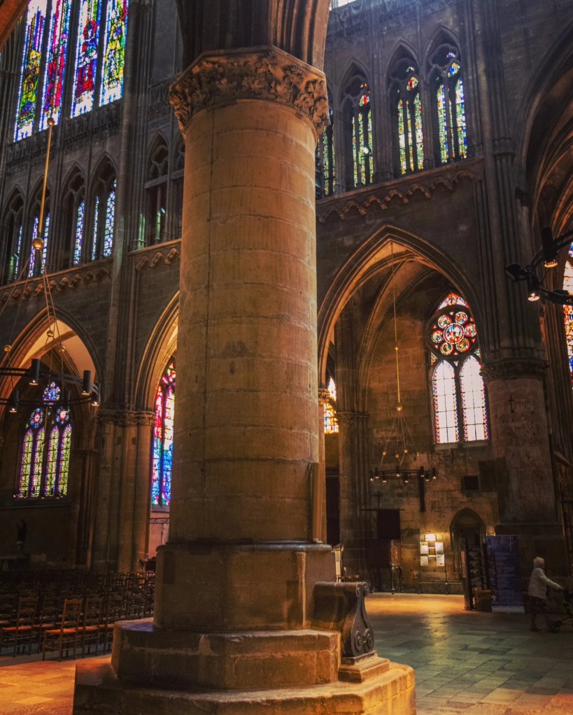 Stone column inside Metz Cathedral with stained-glass windows glowing in the background.