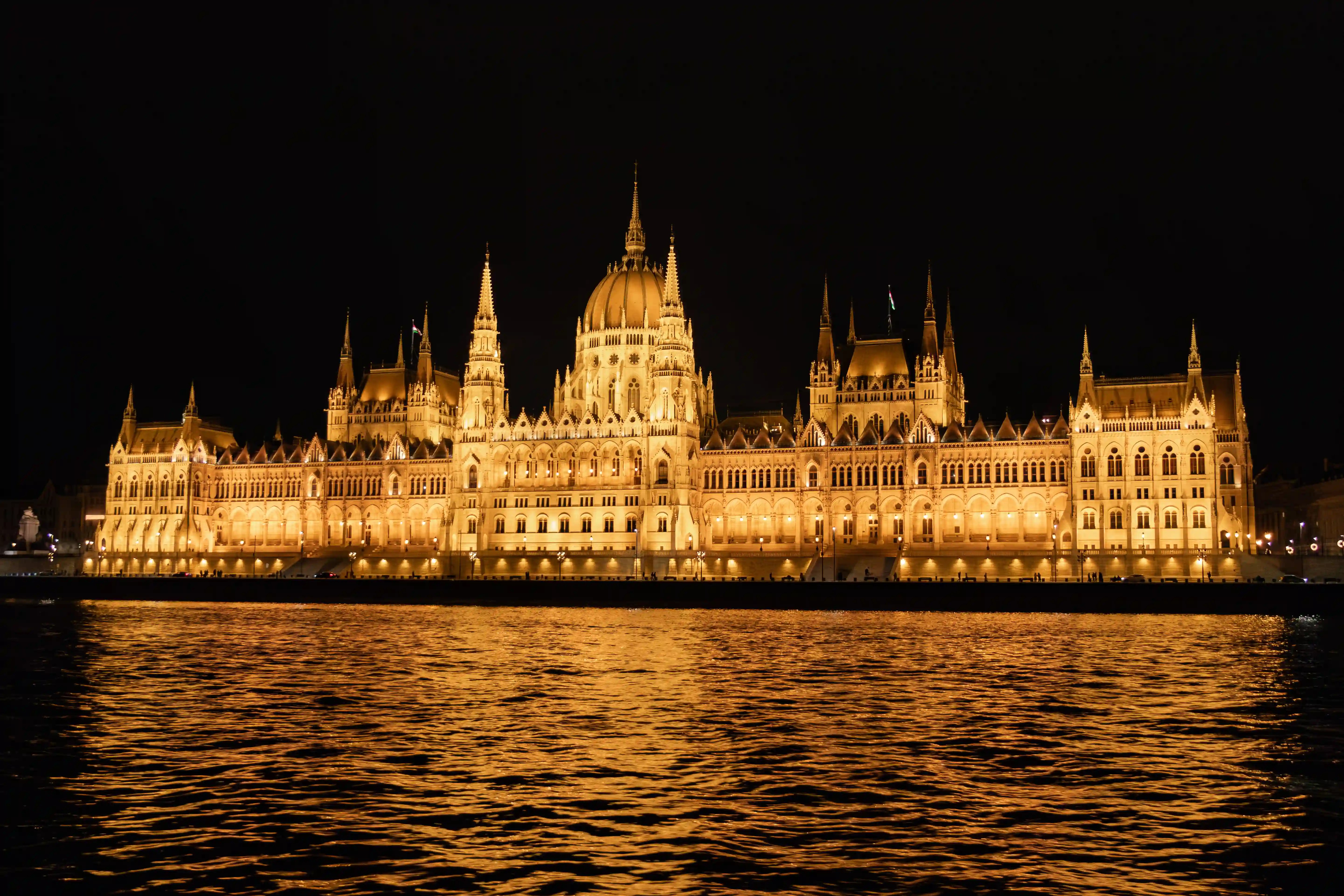 The Hungarian Parliament Building in Budapest illuminated at night, reflected in the dark waters of the Danube River.