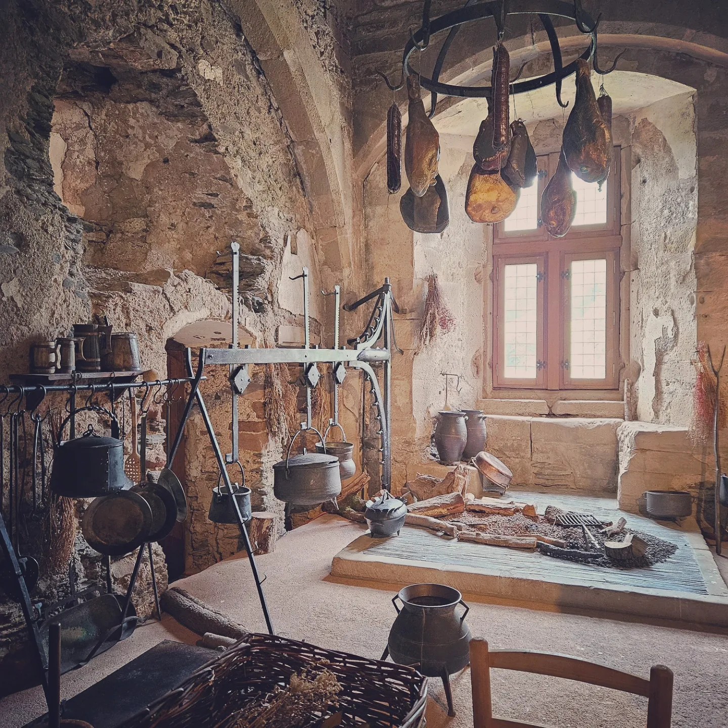 Reconstructed medieval kitchen in Vianden Castle with hanging pots, tools, and fireplace.