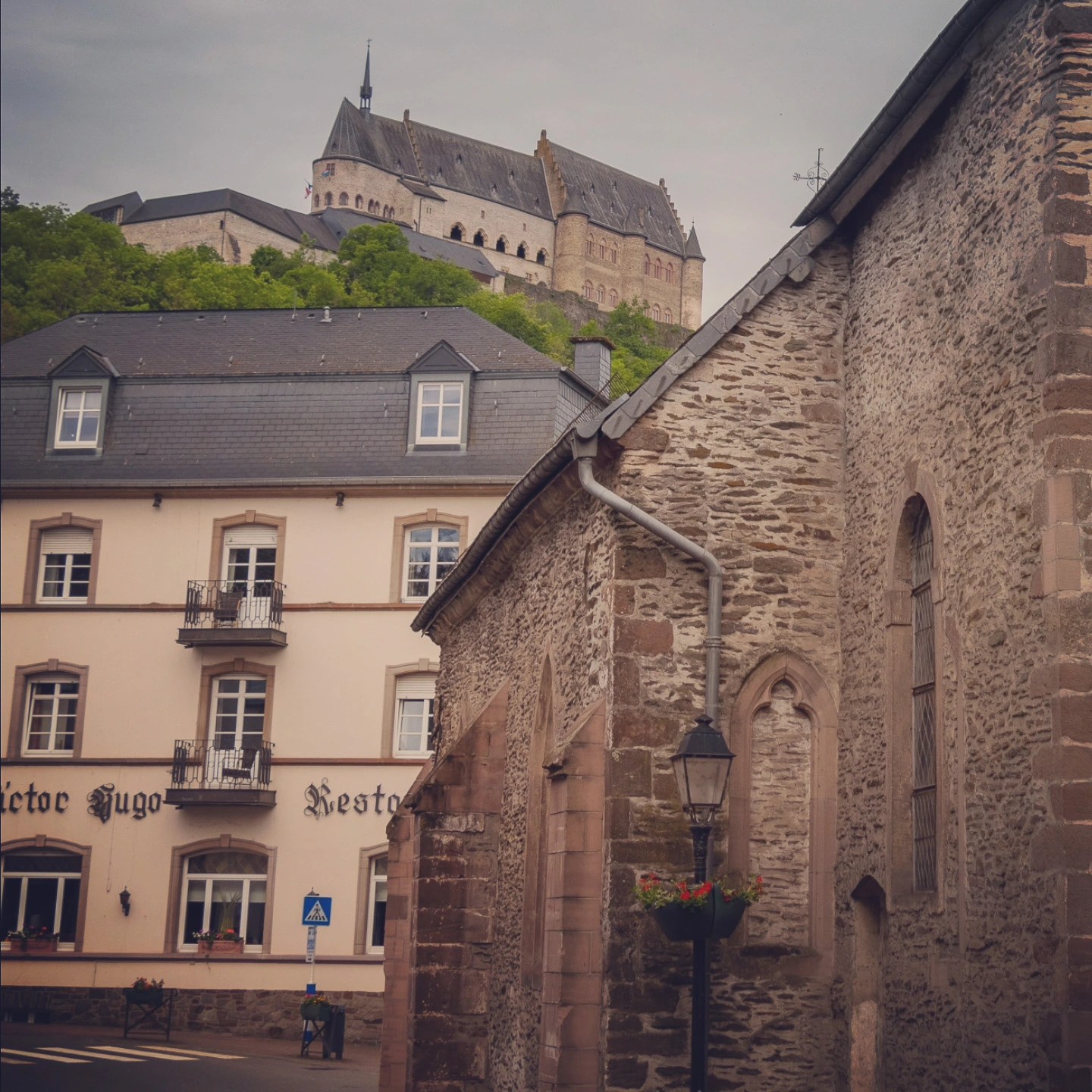 Vianden Castle perched on a forested hilltop with the town’s stone buildings below.