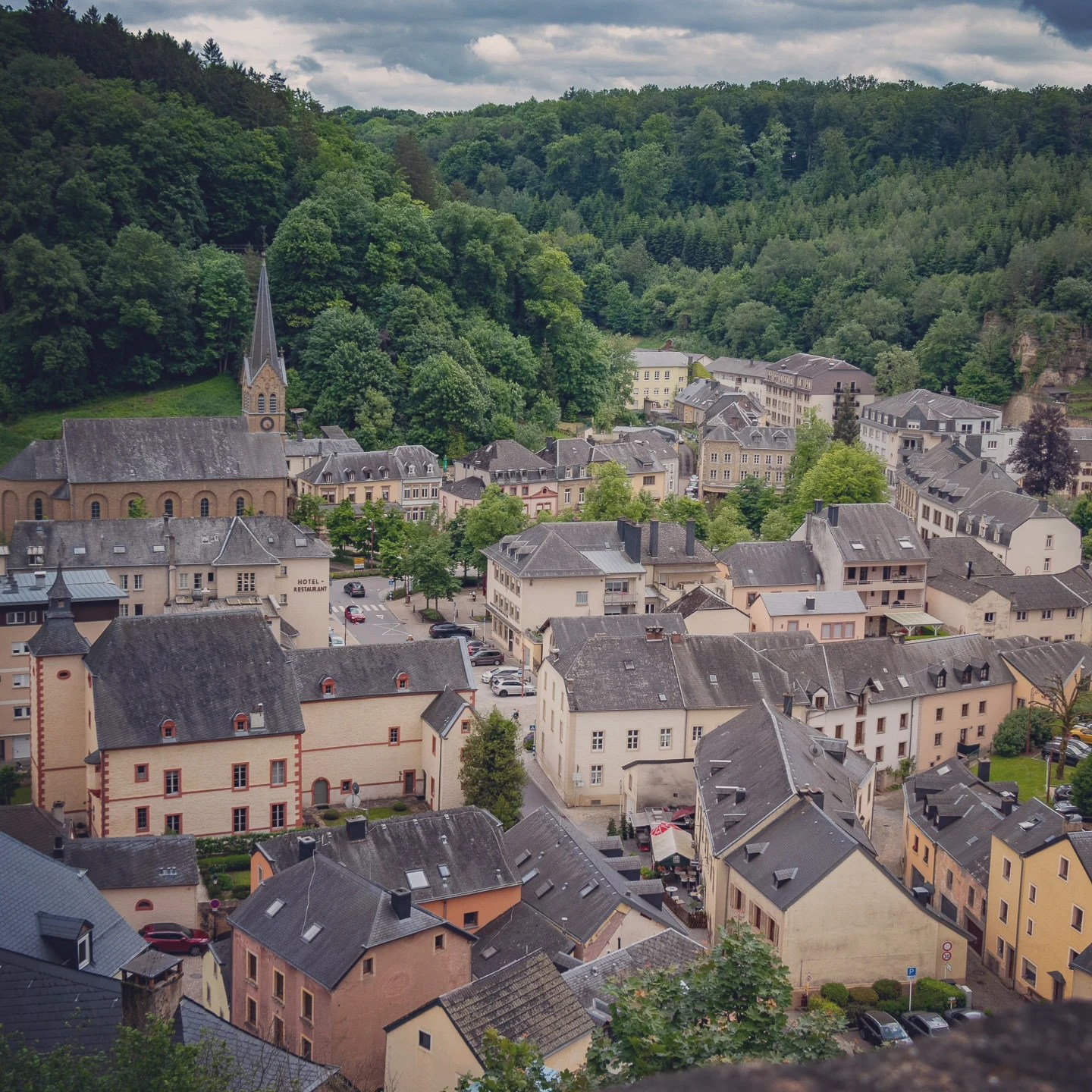 A view over the town of Larochette with clustered rooftops and a church tower.