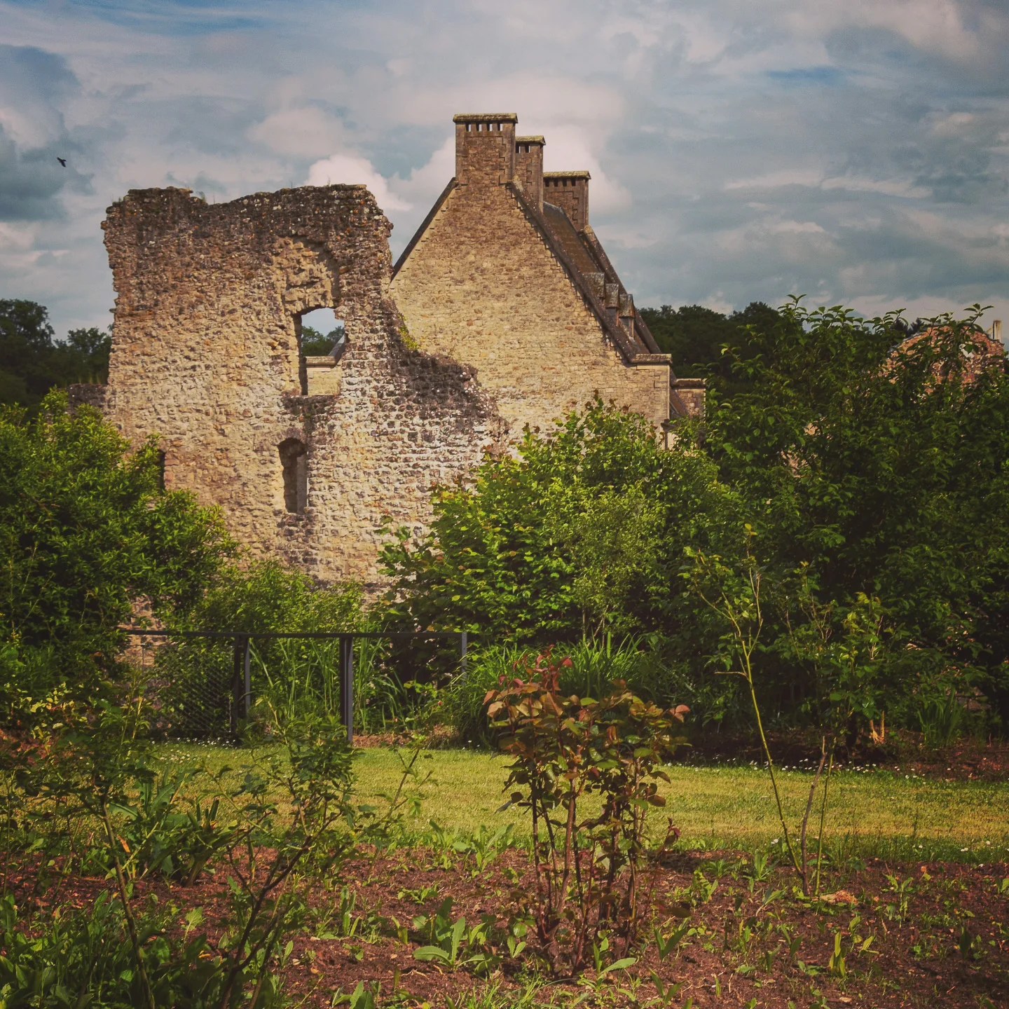 Ruined stone walls of Larochette Castle rising behind a green garden.