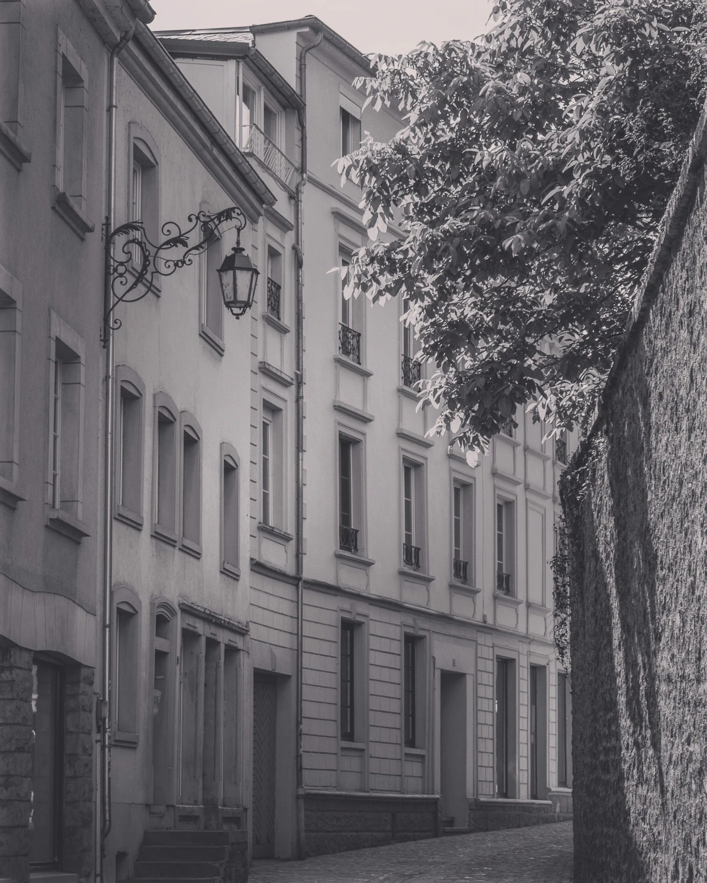 Narrow cobblestone street in Echternach with historic buildings and an ornate streetlamp.