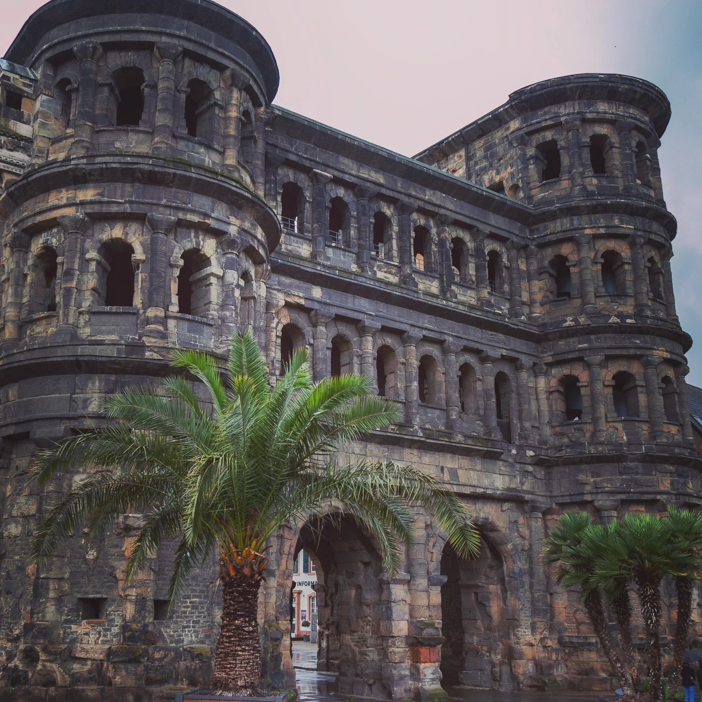 Side view of the Roman Porta Nigra in Trier with palm trees in foreground.