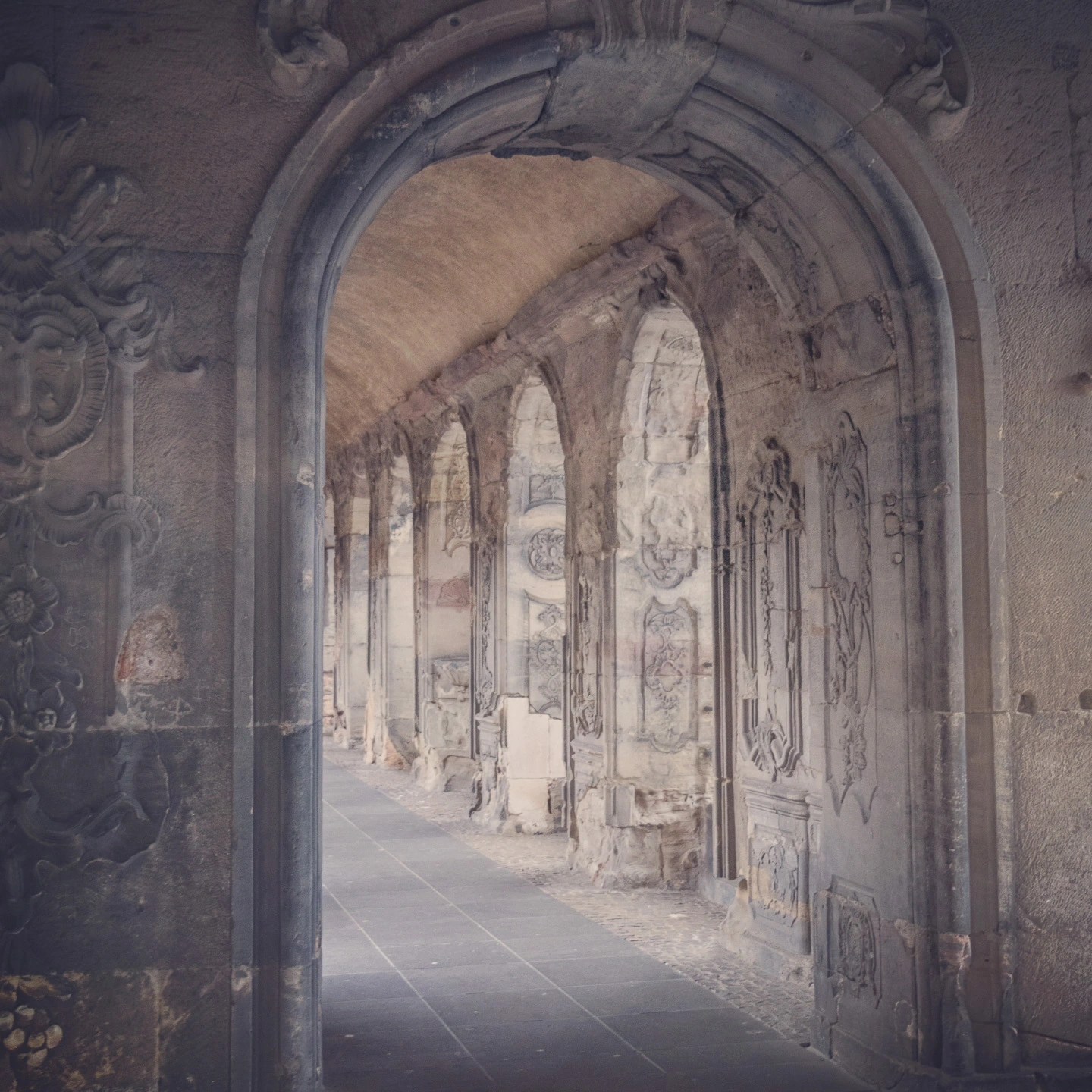 Corridor of stone arches with carved details inside Trier’s Roman Porta Nigra.
