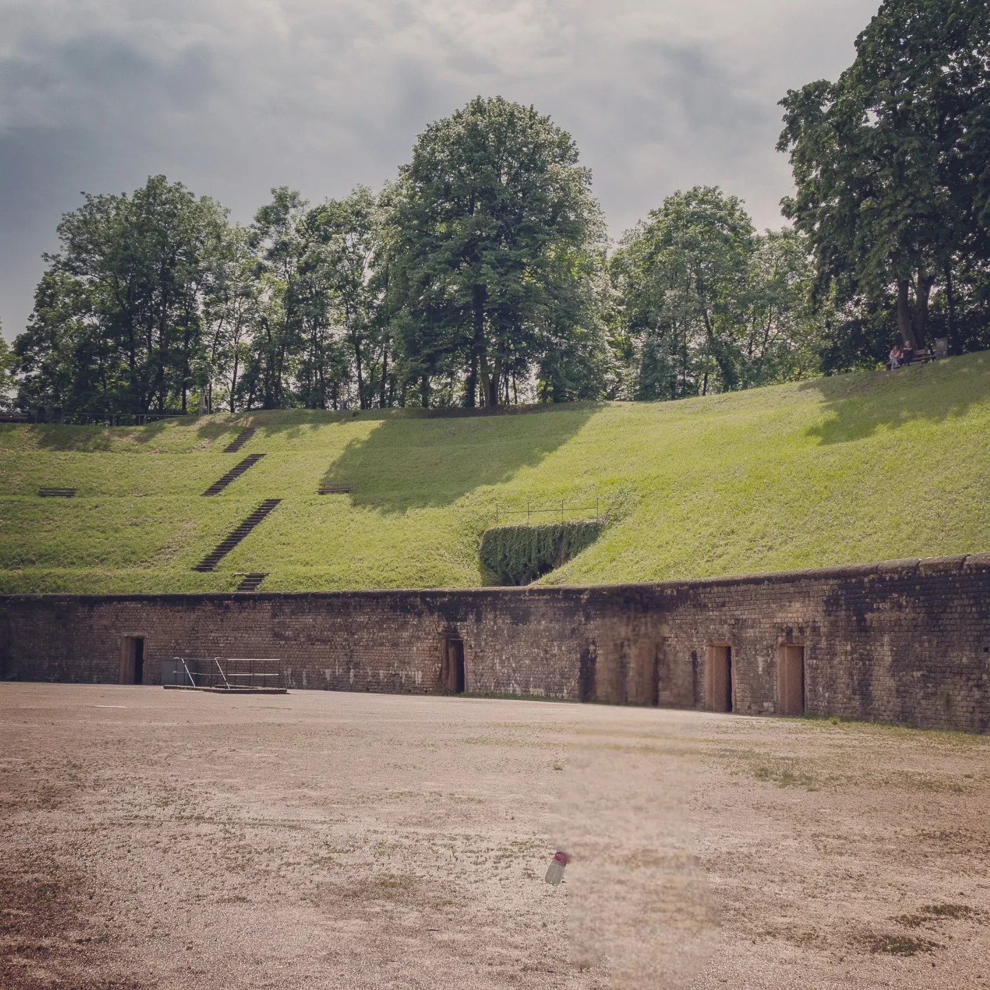 Stone arena wall with arched entrances in Trier’s Roman amphitheater.